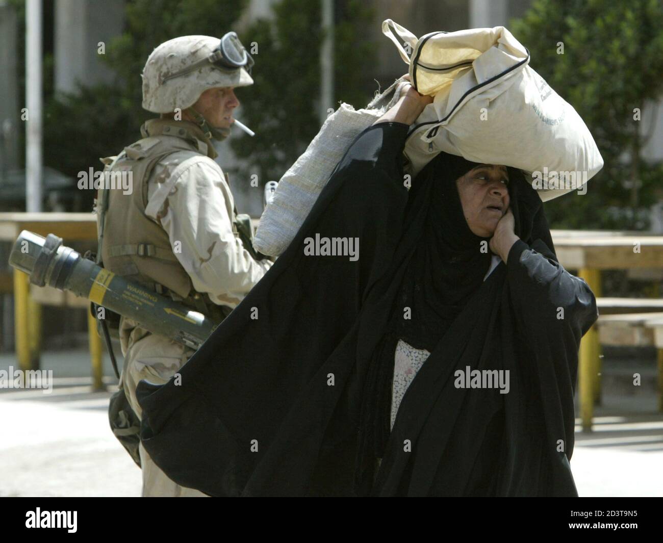 An Iraqi woman walks past a U.S. Marine from Lima Company, a part of a 7th Marine Regiment, as the unit patrols in the northern part of Iraqi capital Baghdad April 10, 2003. U.S. forces in Iraq grappled with looting and civil disorder, scattered gun fights and a suicide bomb attack that took American lives on thursday, one day after the euphoria that marked the end of Saddam Hussein's rule. PP03040034   REUTERS/Oleg Popov  OP/GB Stock Photo