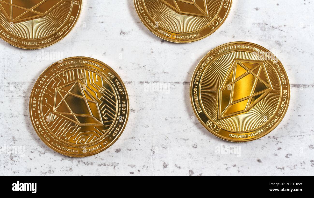 Golden commemorative EOS - EOSIO  cryptocurrency - coins on white stone board, overhead photo Stock Photo