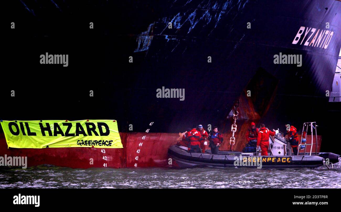 Members of the environmental organisation Greenpeace hang up a banner reading 'oil hazard' on the oil tanker Byzantio in the port of Rotterdam December 4, 2002. The ageing oiltanker is under fire from environmentalists who claims it is posing an oil-spill threat following the disaster of the [Prestige] oil tanker which broke apart at sea off the [Spanish] coast two weeks ago. Stock Photo