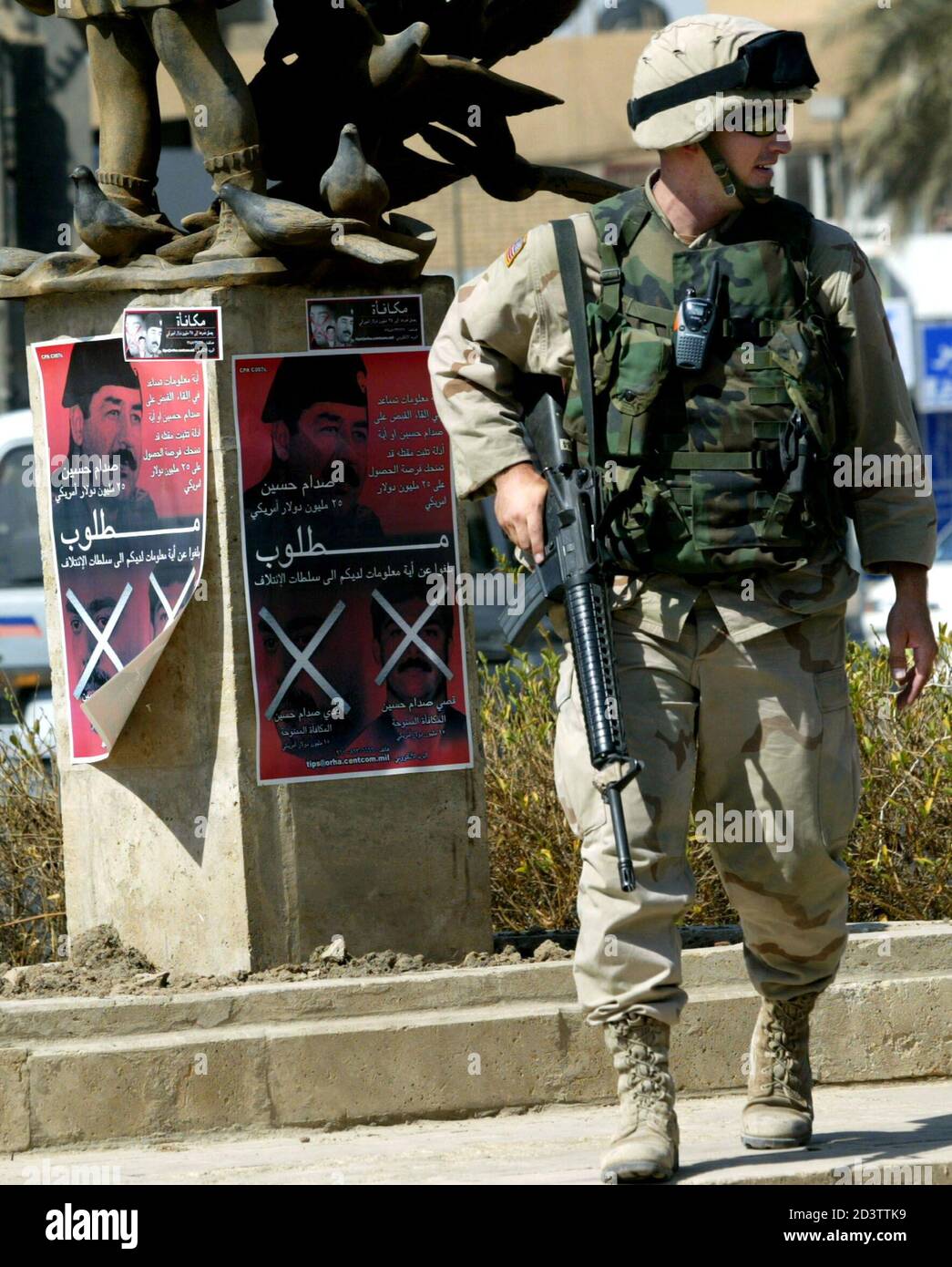 A U.S. soldier passes wanted posters of Saddam Hussein in Baghdad, August  27, 2003. Iraq's U.S.-led administration is hoping the posters and the  prospect of a $25 million reward will encourage Iraqis