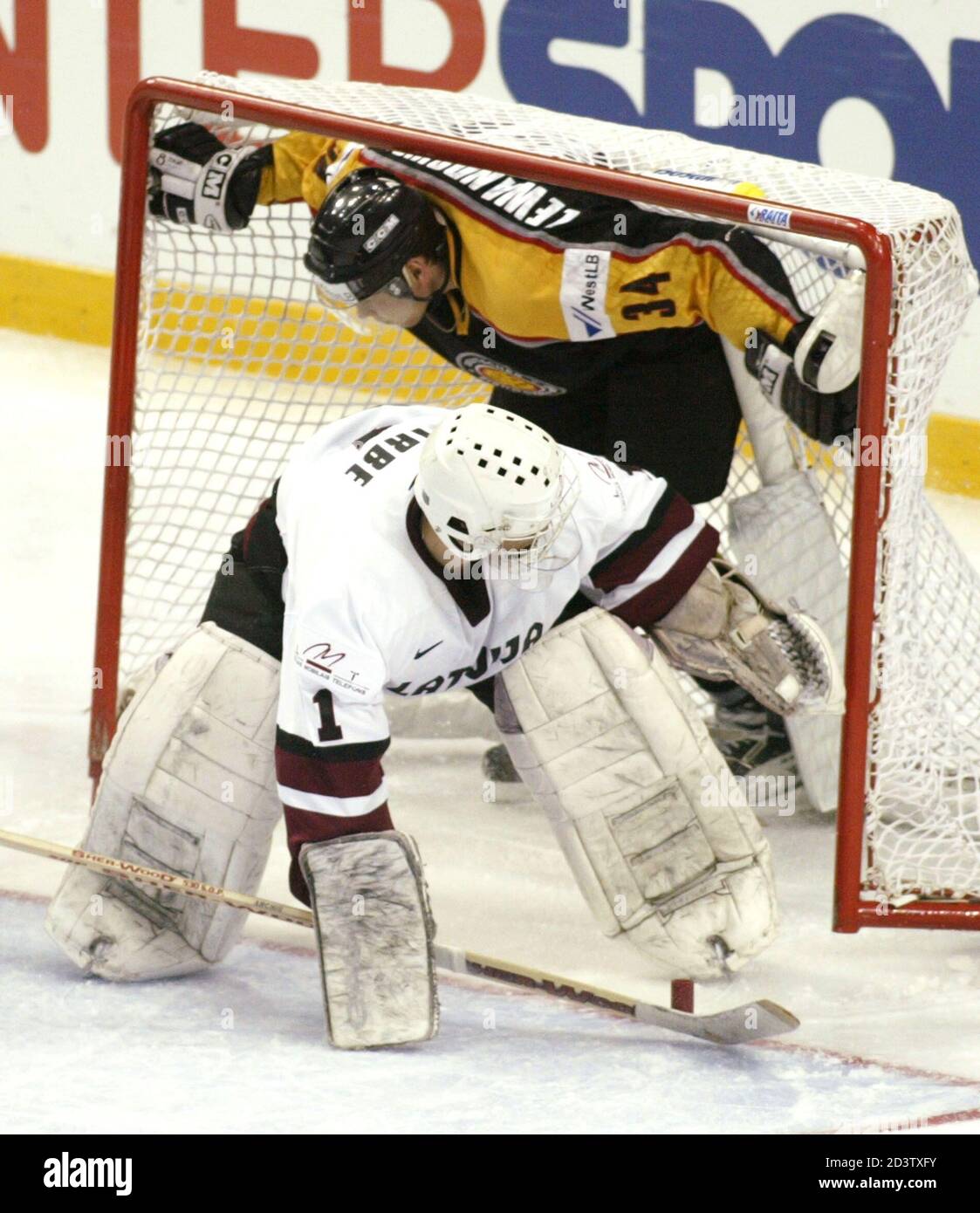 LATVIA'S GOALKEEPER ARTURS IRBE SAVES A PUCK WHILE GERMANY'S EDUARD  LEWANDOWSKI IS PUSHED INTO HIS CAGE. Latvia's goalkeeper Arturs Irbe saves  a puck while Germany's Eduard Lewandowski is pushed into his cage