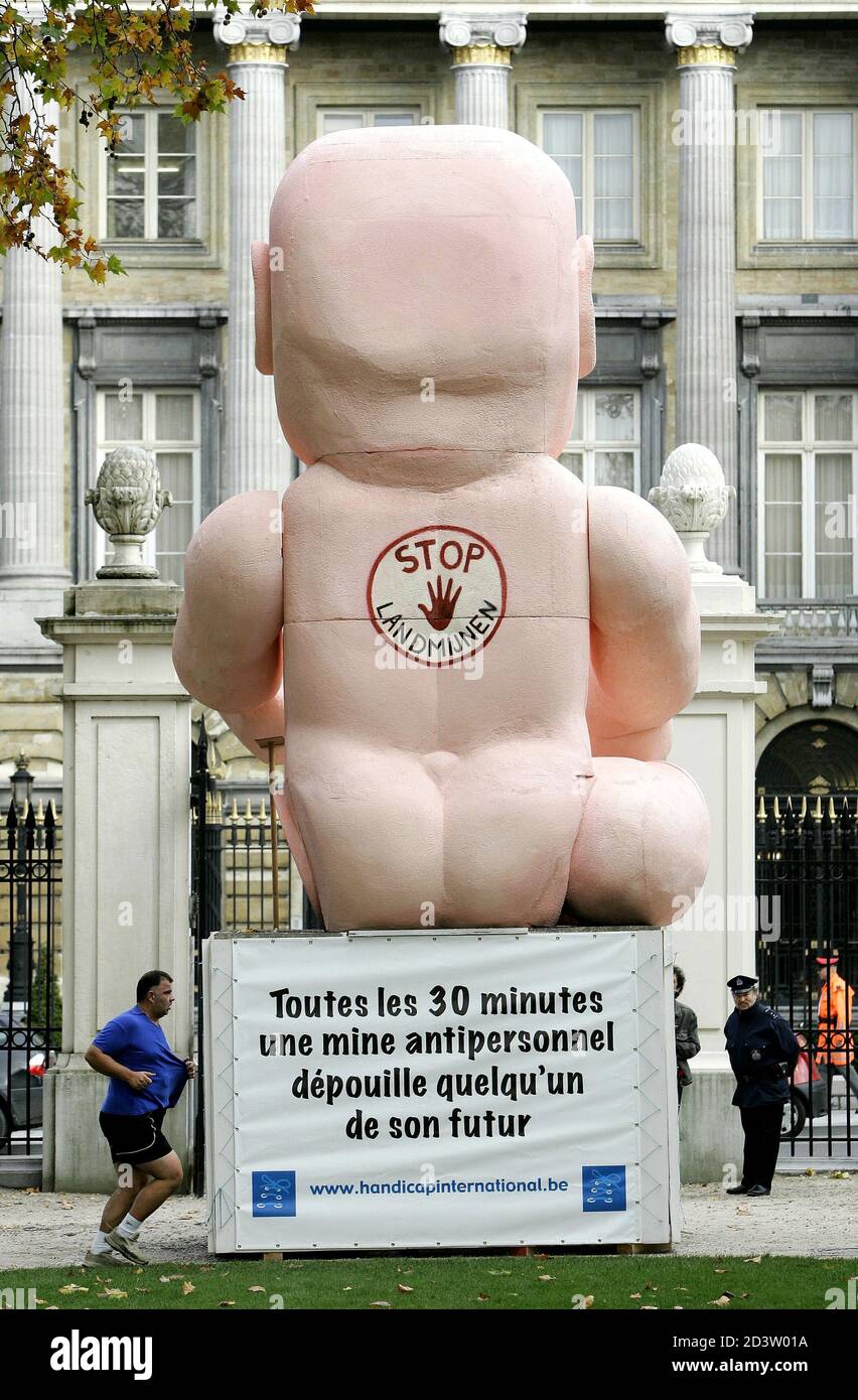A jogger runs past a giant doll with one leg missing in Brussels Royal Park  October 28, 2004. The disabled doll is part of a campaign launched by  Handicap International to raise