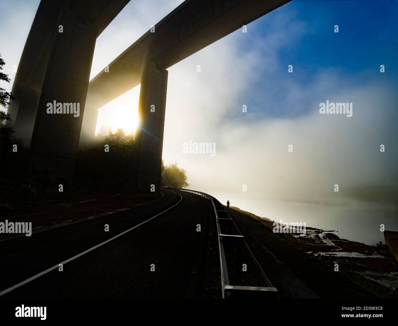 Big enormous large vs small diminutive petite tiny against light silhouette contre-jour contrejour human figure against massive highway bridge ovehead Stock Photo