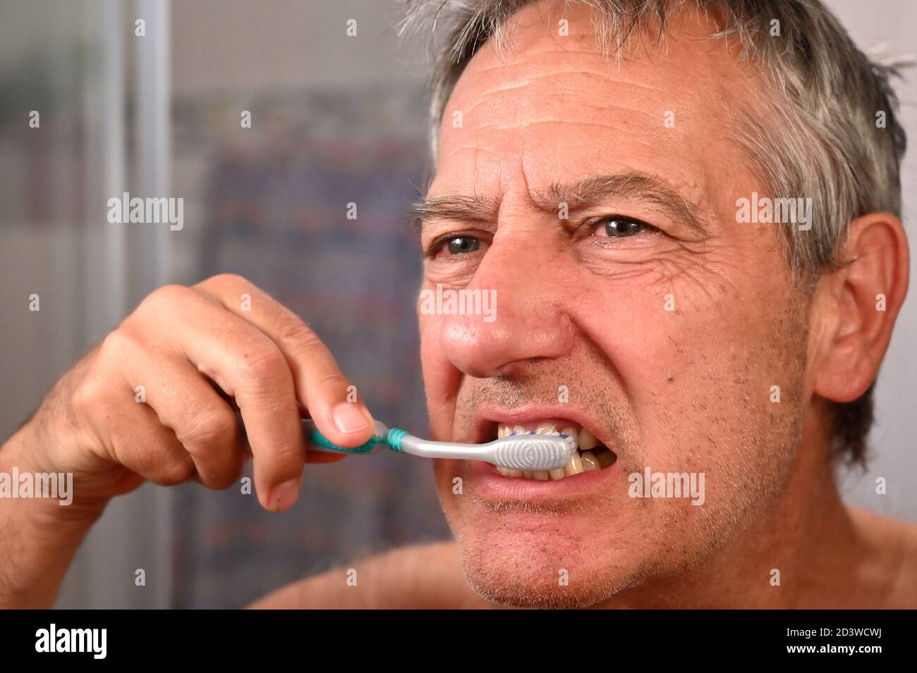 Senior male in the bathroom with using a tooth brush Stock Photo