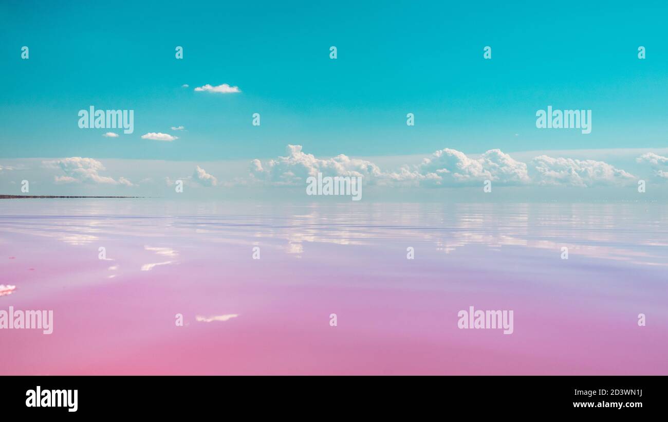 Pink salt lake water surface close-up with mirror reflection of magic clouds with blue sky, color graded Stock Photo