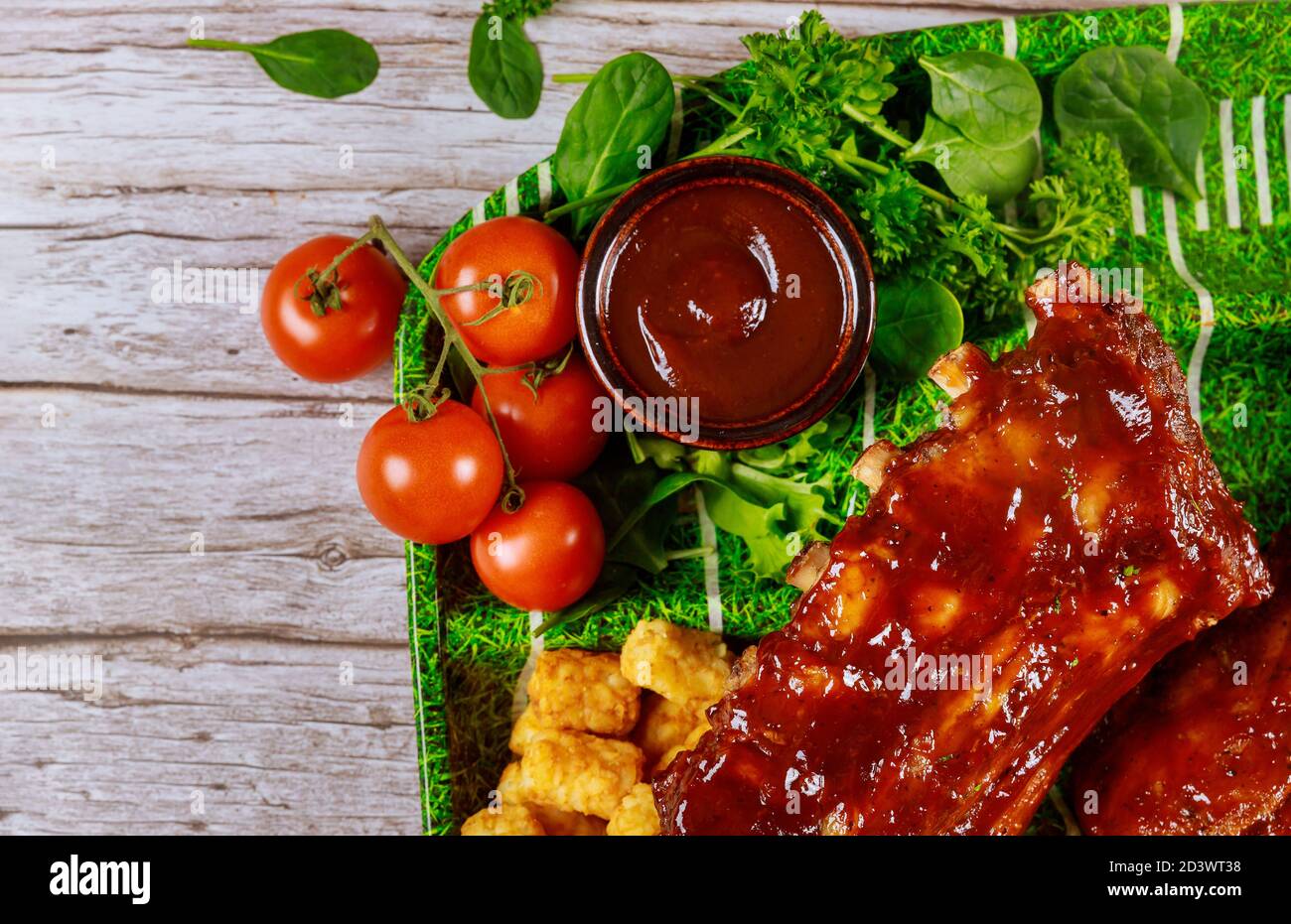 Pork ribs with barbecue sauce on black stone board. Top view with copy