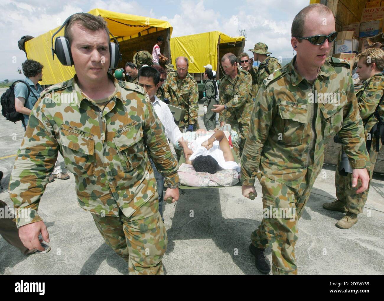 Australian soldiers at Banda Aceh airport carry an injured Acehnese January 4, 2005. Aid workers cleared landing strips in Asia's flooded tsunami-hit regions to start flying food, clean water and doctors to hungry and injured survivors, but the global relief operation continued to struggle on Tuesday. REUTERS/Kim Kyung-Hoon  KKH Stock Photo