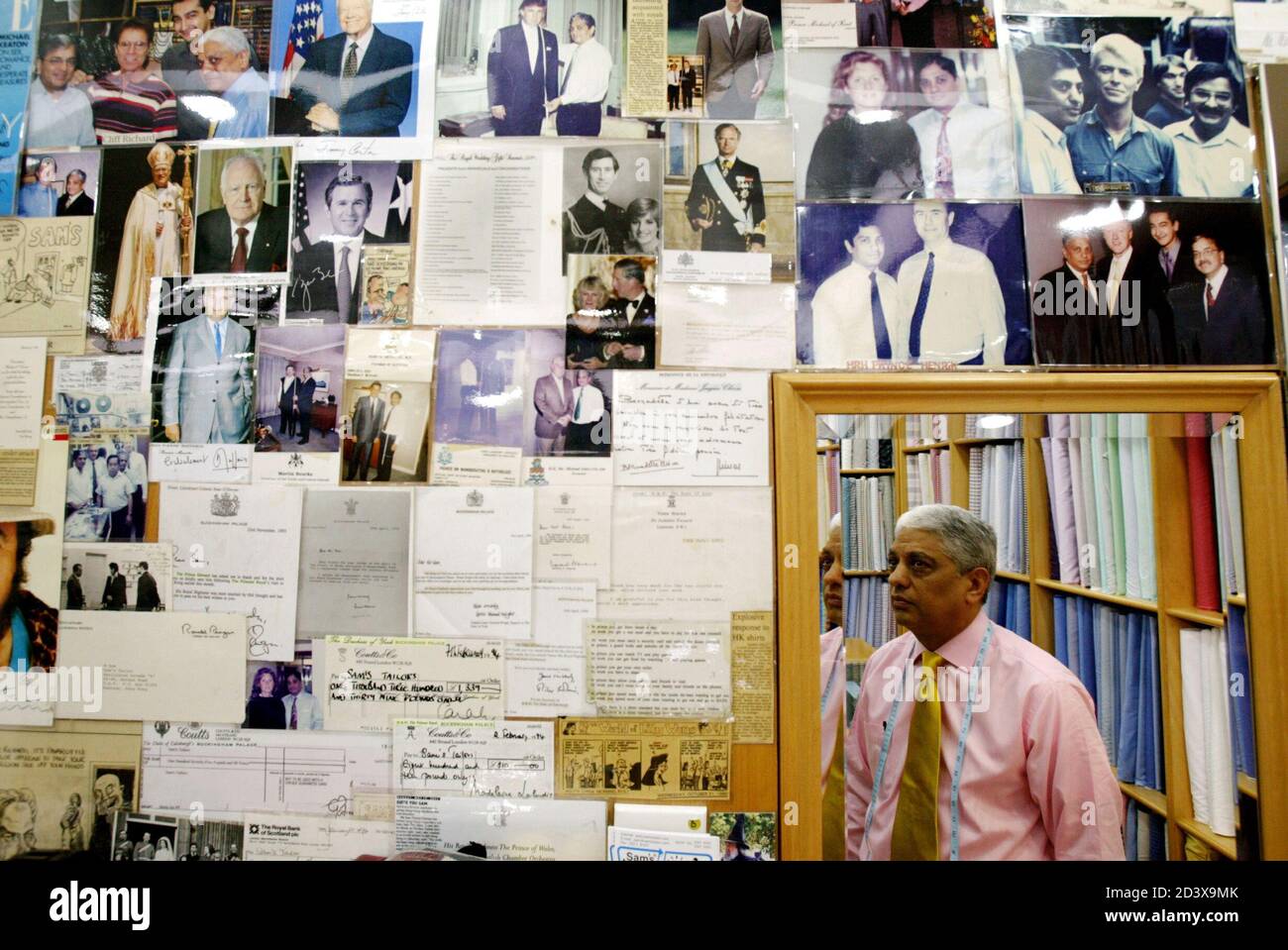 Photo Taken 16dec03 Manu Melwani Or Sam The Tailor Is Reflected In A Mirror As He Looks At Snapshots And Letters From His Clients Inside His Shop In Hong Kong At the heart of indian directory is first online directory of indian business community in hong kong:
