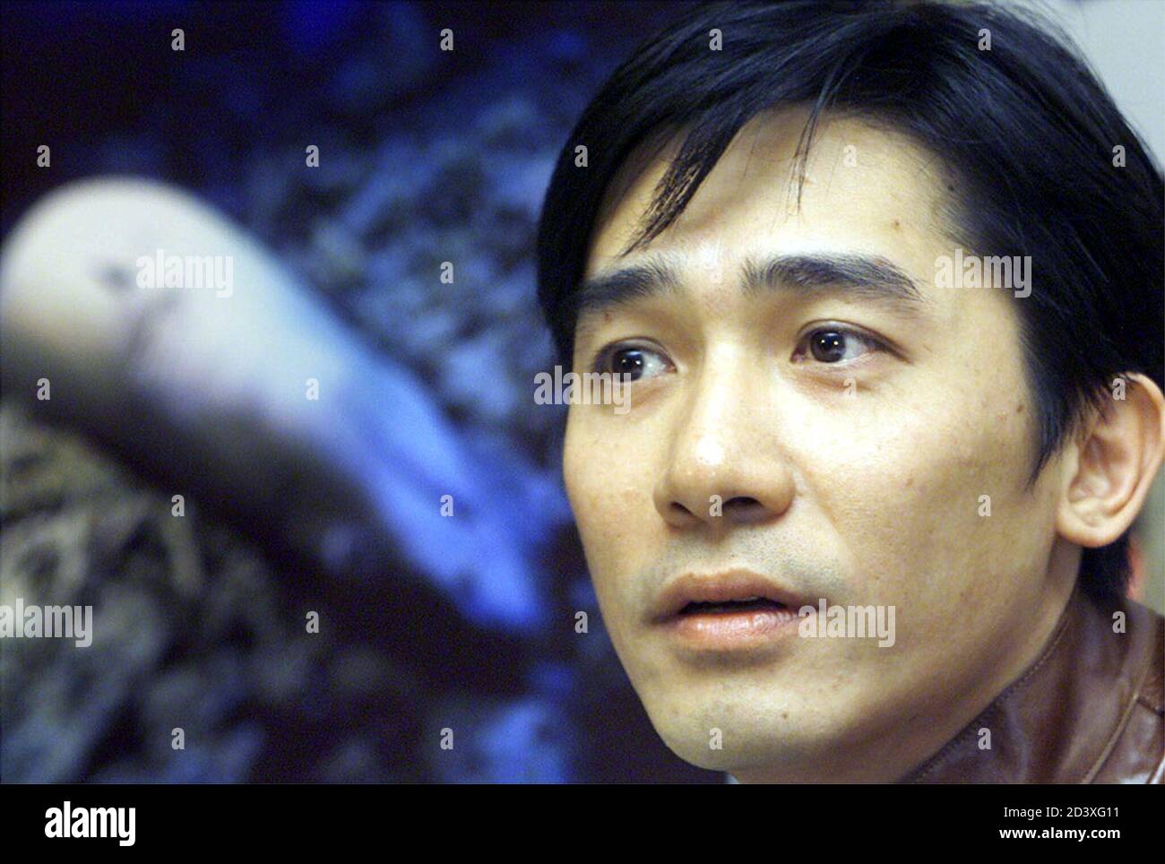 Hong Kong actor Tony Leung waits for questions in front of a poster showing a shark being dumped into the ocean after fishermen had sliced off its fins for trade during a news conference in Hong Kong March 15, 2001. Leung has been named the Enviromental Ambassador of WildAid, an international conservation group campaigning for the protection of sharks. Stock Photo