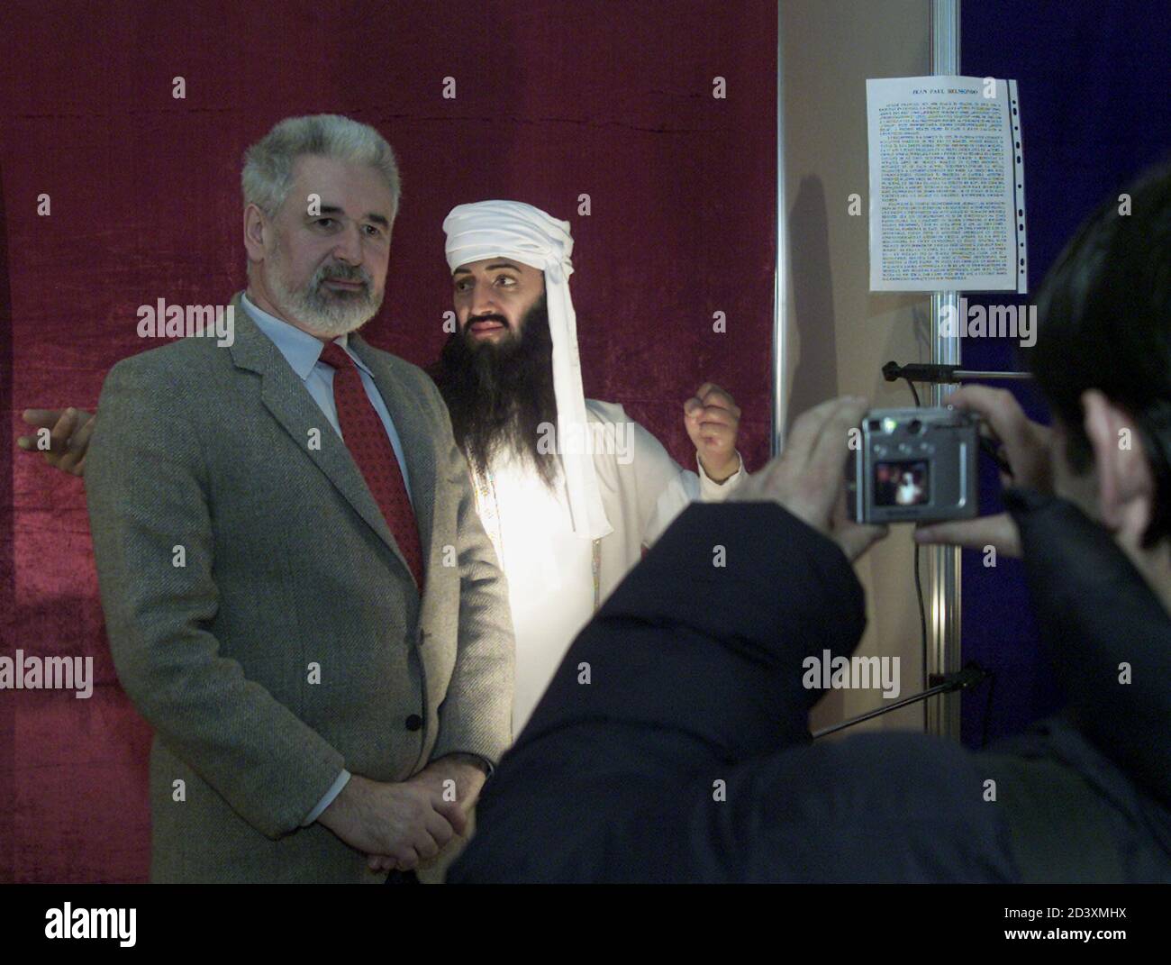 A visitor poses for a photograph next to a wax statue of Ossama Bin Laden at Bucharest's City Museum, where a travelling exhibition from Saint Petersburg' wax museum which opened on January 23, 2003. The show includes 27 wax statues of international celebrities, such as politicians and Hollywood actors, as well as historical characters and will stay in Romania for two months. REUTERS/Bogdan Cristel REUTERS  BC Stock Photo