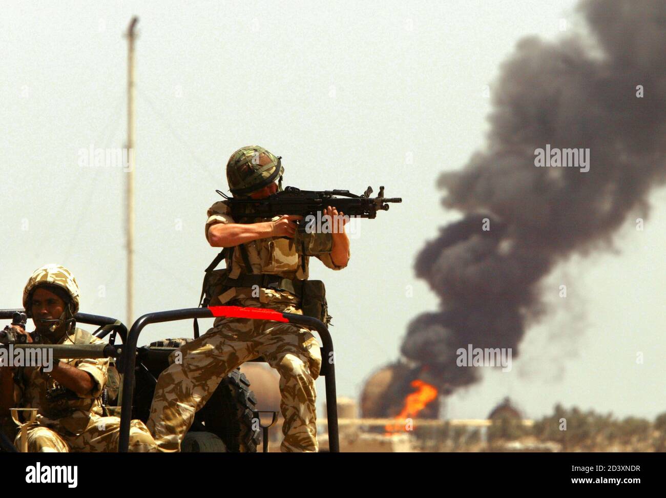 British soldiers aim their guns as they provide security on a road next to a burning liquid gas depot near Al Zubayr near Basra April 14, 2003. British forces said that the depot was looted before the fire broke out. Coalition forces blocked traffic in the main motorway leading to Baghdad as an explosion would effect an area of 6 km radius. REUTERS/Yannis Behrakis  YB/MA Stock Photo