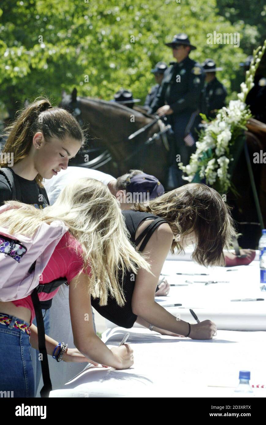 Young girls sign a condolence poster before the memorial for former NFL player Pat Tillman, in the San Jose Memorial Rose Garden, May 3, 2004. Tillman, who played professional football for the Arizona Cardinals, turned down a $3.6 million contract from the team to sign up with the Army in 2002. He was killed in combat in Afghanistan on April 22, 2004. He was awarded the U.S. military's prestigious Silver Star posthumously, the Army Special Forces Command said. REUTERS/Susan Ragan  SR/HK Stock Photo