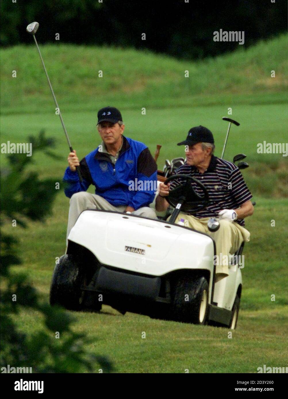 President George W. Bush (L) rides in a golf cart driven by his father, former President George Bush (R), as they play an early morning round of golf together at Cape Arundel Golf Club July 6, 2001 in Kennebunkport, Maine.The two men were wearing matching caps marked '43' and '41,' referring to the numbers of their presidencies. Stock Photo