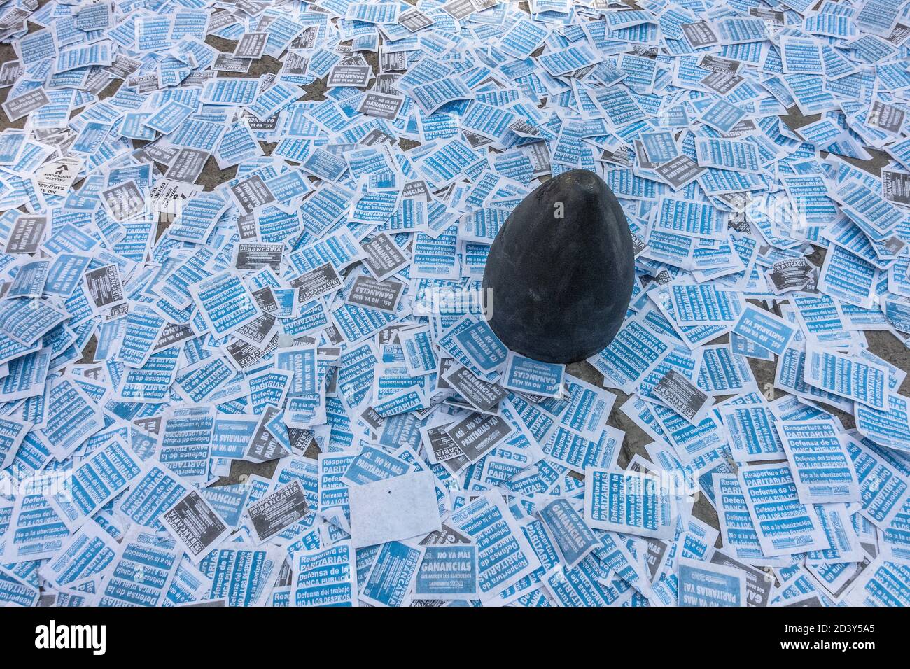 Anti austerity leaflets litter the street around a bollard in Buenos Aires, Argentina Stock Photo