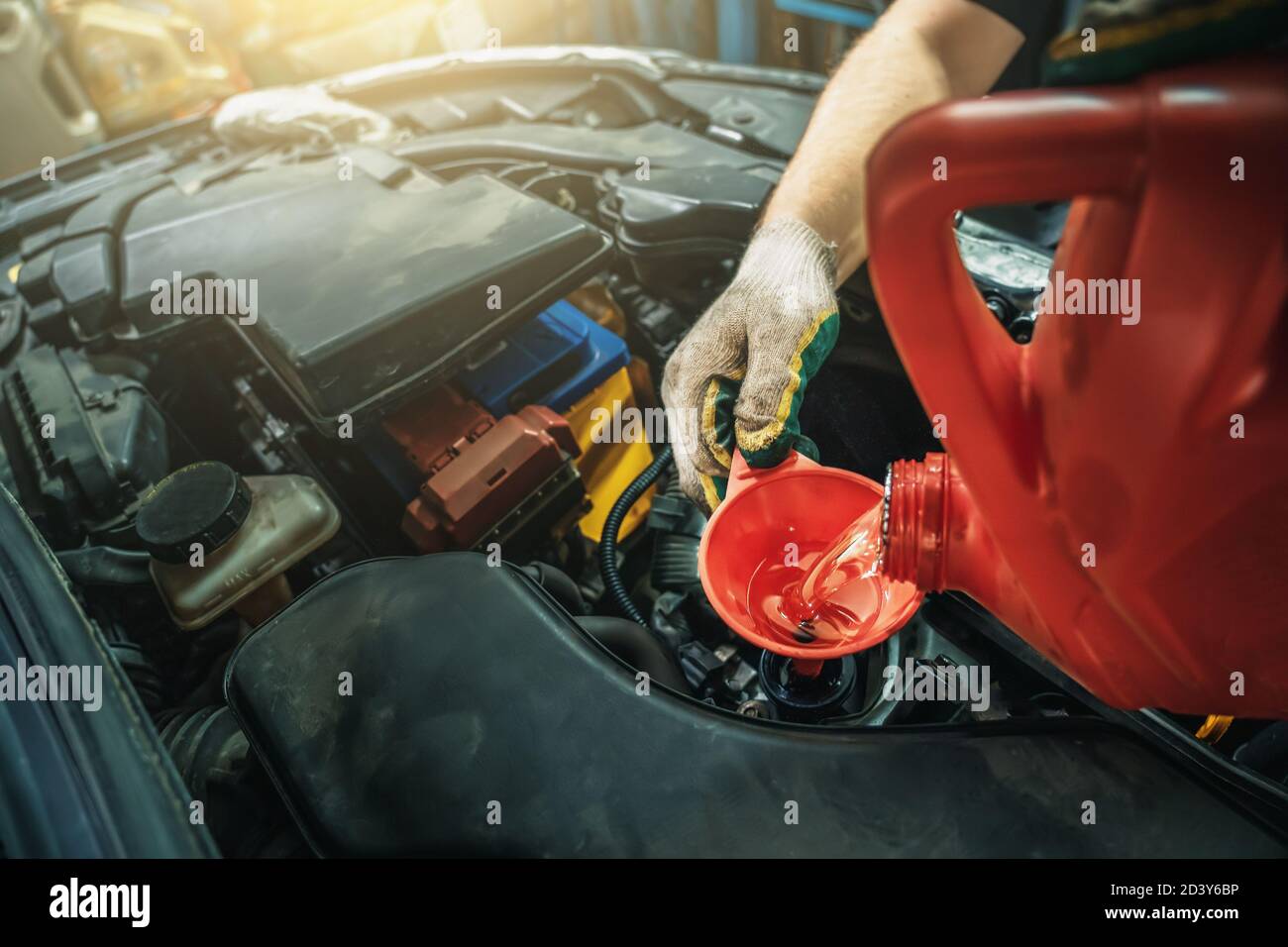 New engine oil pours from canister into motor at car service, close up. Stock Photo