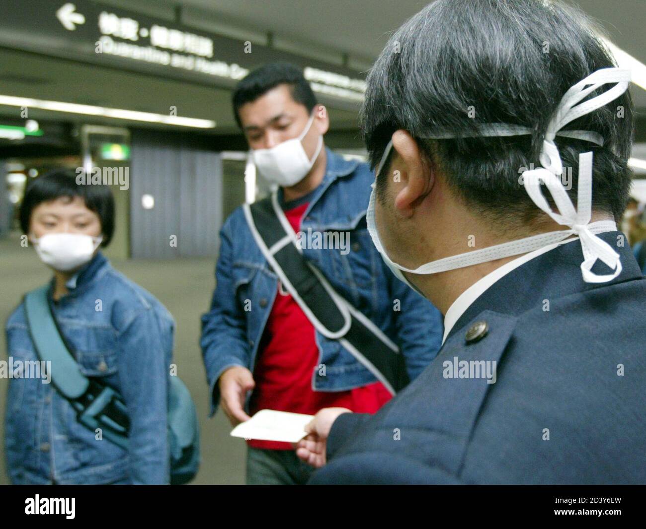 JAPANESE QUARANTINE OFFICIAL WEARING MASK HANDS OUT LEAFLET ON SARS TO