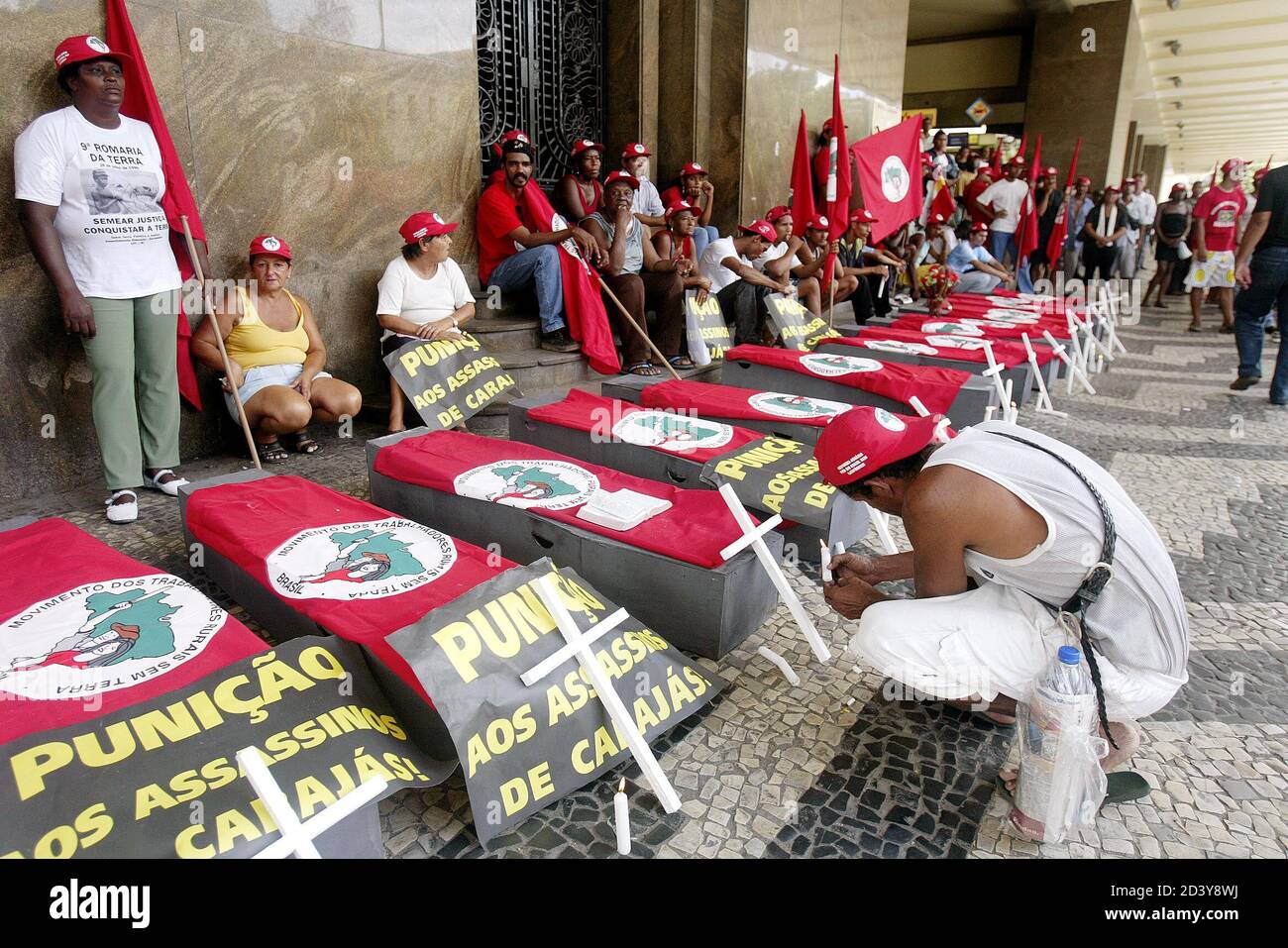 A member of Brazil's Landless Movement (MST) lights a candle next to coffins during a demonstration in Rio de Janeiro April 16, 2004, marking the eighth anniversary of a police massacre of 19 rural workers. Landless workers, trade unions and Roman Catholic Church groups have called for a day of protests to remember those killed in the 1996 massacre in which police opened fire on farmers demanding land in the remote in Eldorado dos Carajas, Northeastern Brazil. REUTERS/Sergio Moraes SM/HB Stock Photo