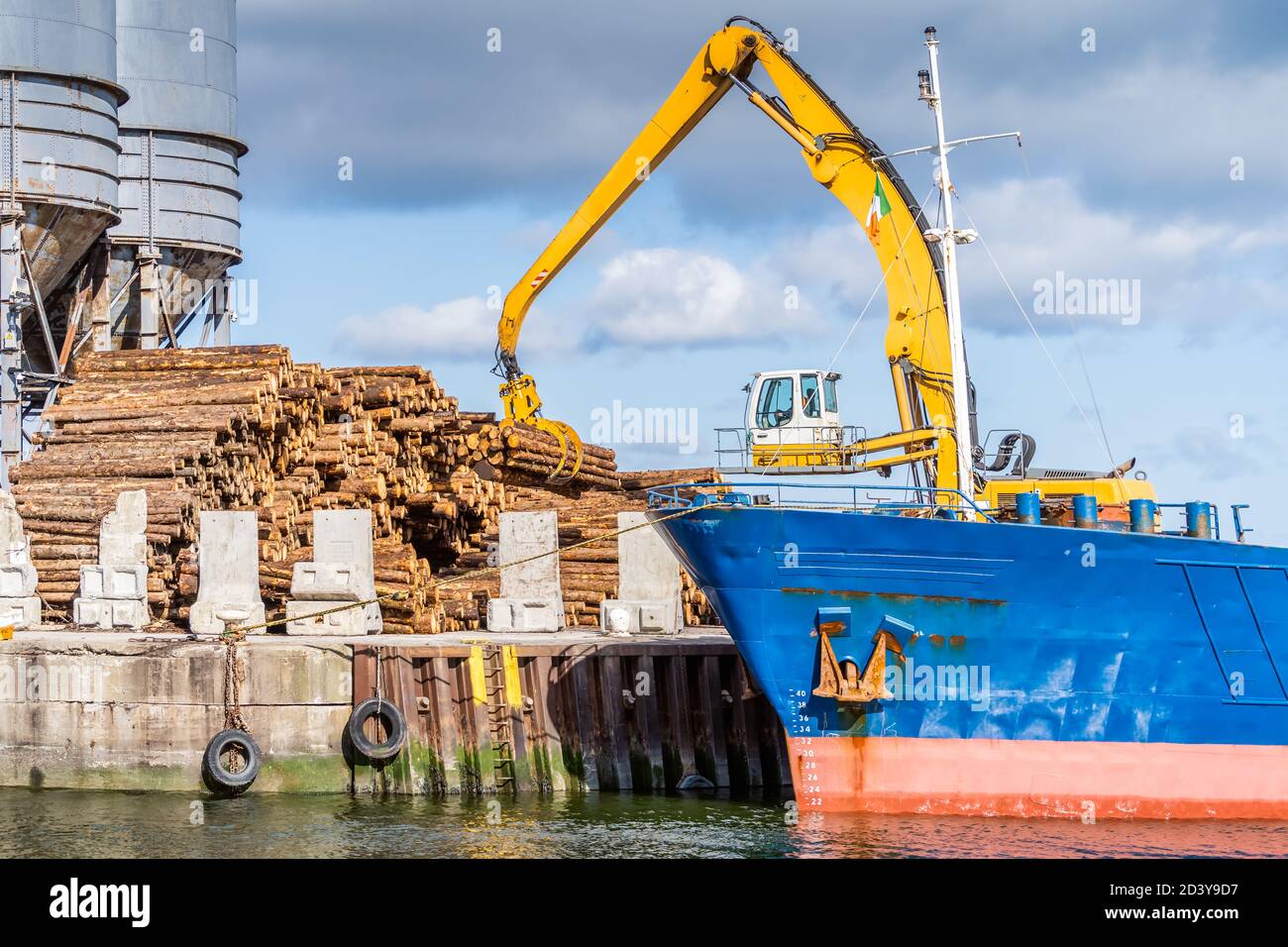 Crane with wood logs gripple loading timber on cargo ship for export in Wicklow commercial port