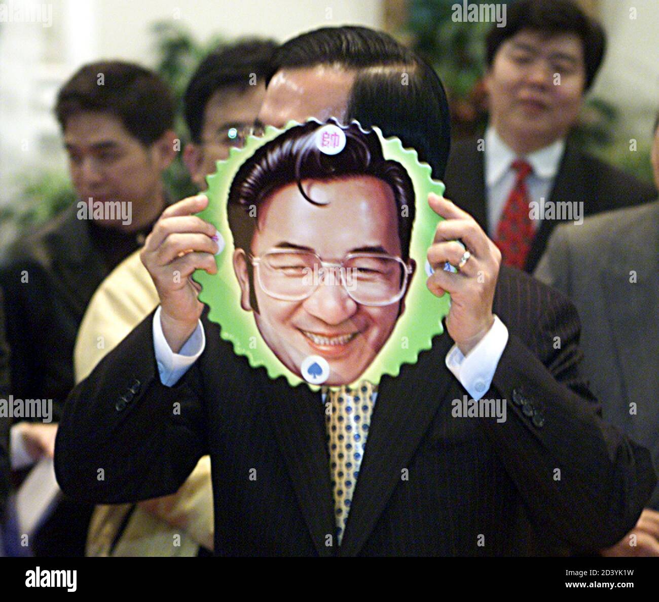 Taiwan President Chen Shui-bian holds up a 'Elvis Presley-style' mask of himself as a group of carcaturists look on at the Presidential Palace in Taipei on March 18, 2003, the third-year anniversary of his election. Analysts say domestic issues, especially Taiwan's slowly recovering economy, will be key to his re-election bid in 2004. REUTERS/Simon Kwong  SK/PB Stock Photo