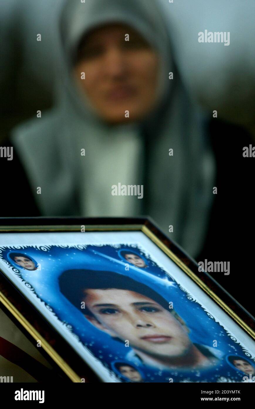 A PALESTINIAN WOMAN WEEPS BEHIND A PICTURE OF A RELATIVE WHO WAS KILLED DURING THE SECOND PALESTINIAN UPRISING AT THE EL SOHADA CEMENTARY AFTER THE LAST PRAYER OF RAMADAN OUTSIDE GAZA CITY. Stock Photo
