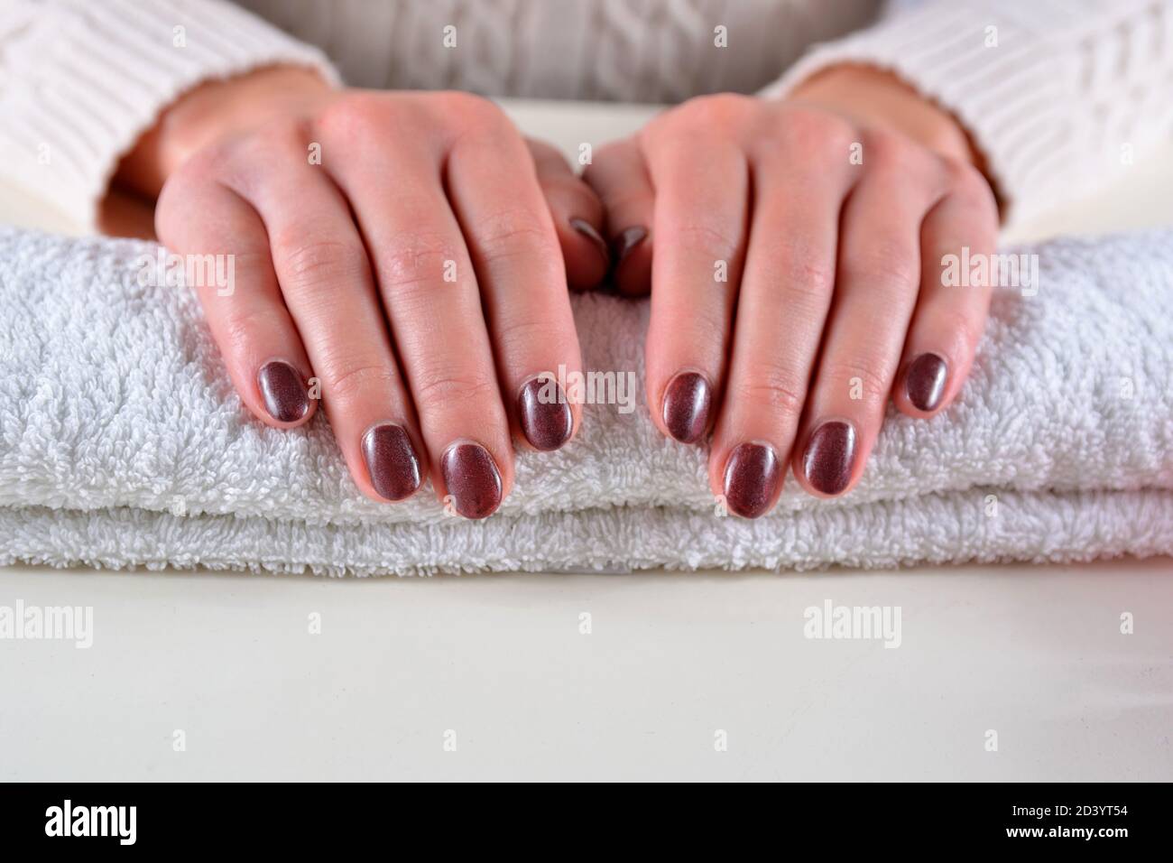 Girl hands with brown nails polish color on a towel in a beauty salon on a  white desk. Manicure and beauty concept Stock Photo - Alamy