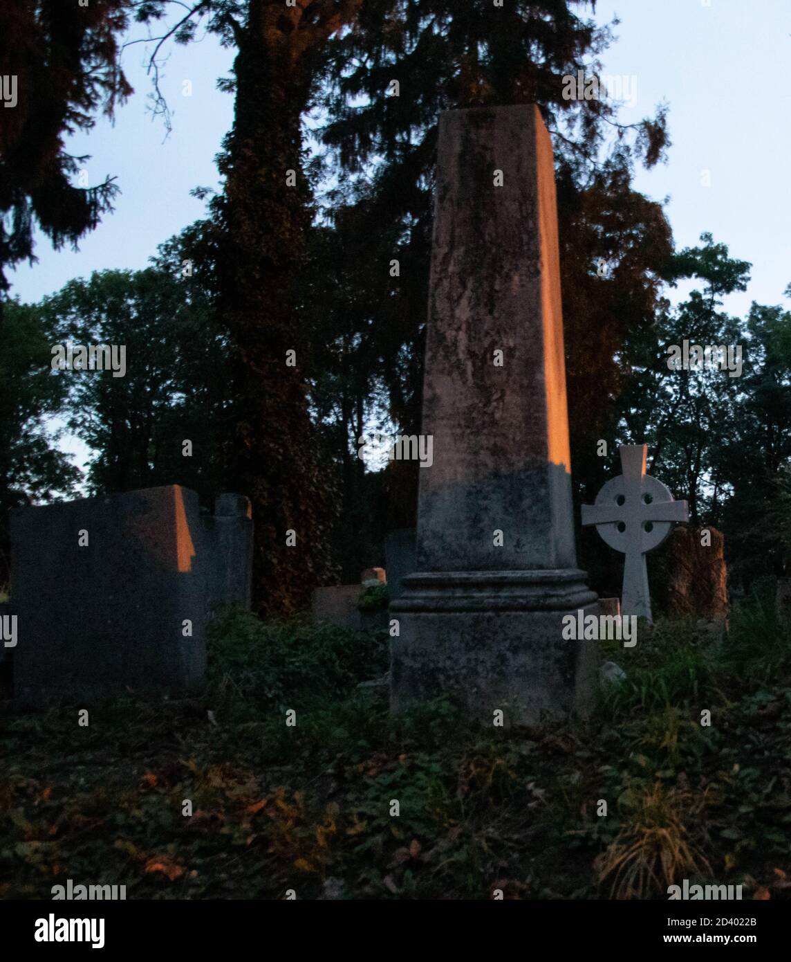 An aged gravestone in an old cemetery during the sunset.the sun's rays are on the side of the grave. Stock Photo