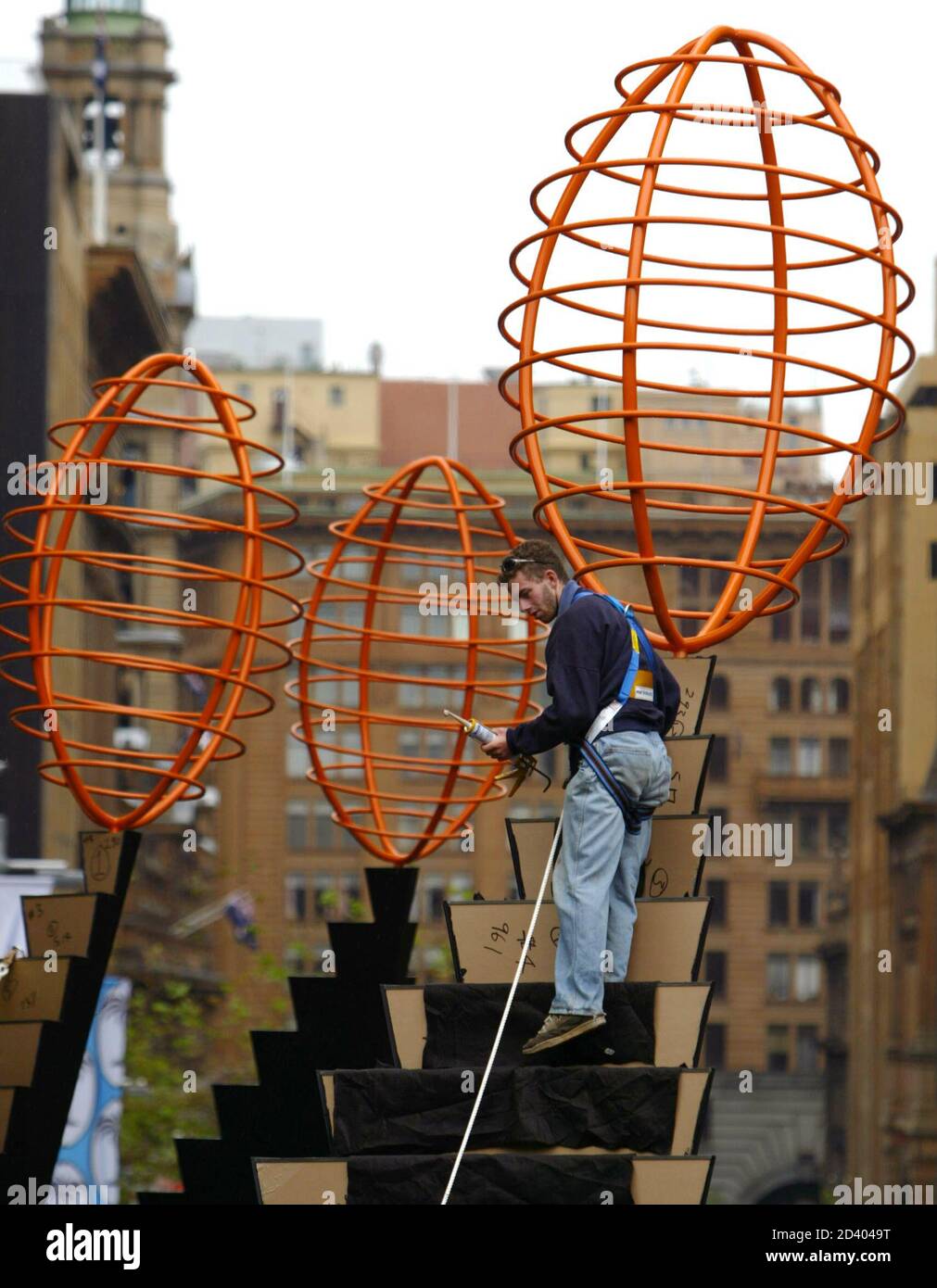 A workman stands amidst an artwork crowned with a stylised steel rugby balls in central Sydney October 6, 2003. The sculpture, one of four, is in the centre of a pedestrian thoroughfare and is designed to promote the Rugby World Cup, a six-week-long rugby tournament contested by 20 nations which starts October 10. REUTERS/Will Burgess  WB/CP Stock Photo
