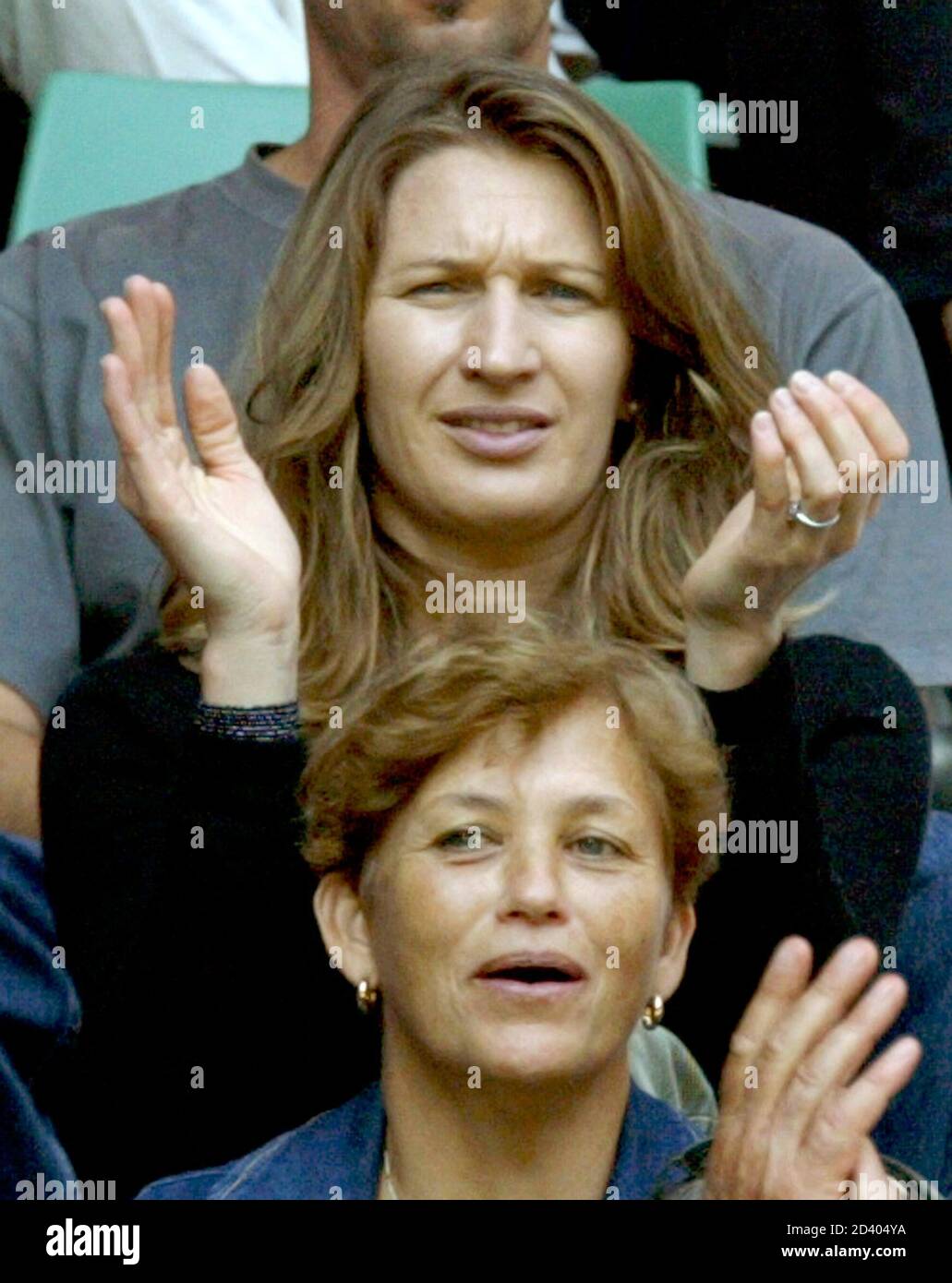 Former German tennis play Steffi Graf (behind) applauds as she watches her  husband Andre Agassi of the U.S. play his quarter-final match against  France's Sebastien Grosjean at the Australian Open tennis championship