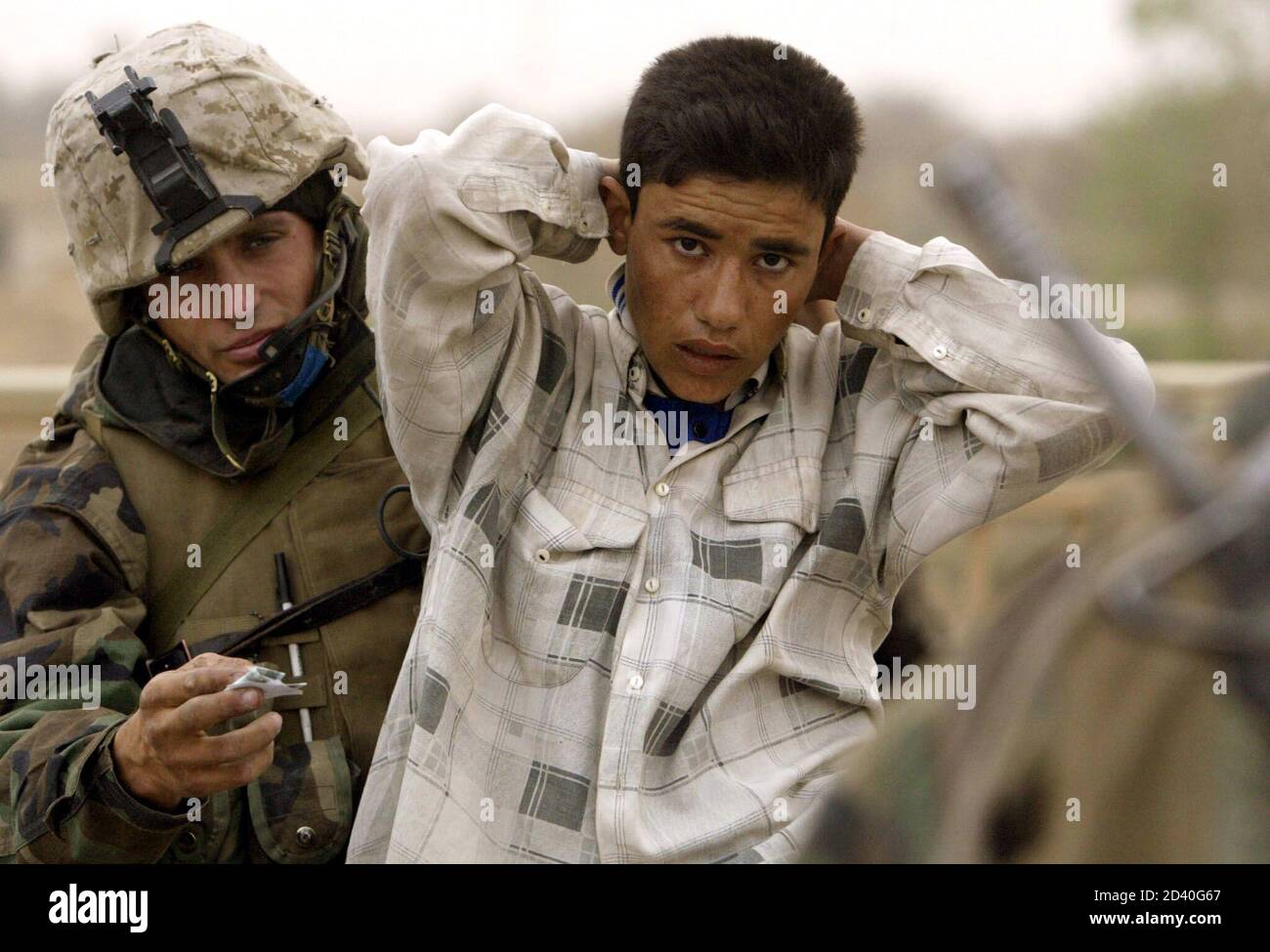 A U.S. Marine from Lima Company, a part of the 7th Marine Regiment, searches a member of the Iraqi Republican guard dressed in civilian clothes for weapons on the New Baghdad highway bridge in the suburbs of the Iraqi capital Baghdad on April 7, 2003.  [U.S. forces burst into the heart of Baghdad on Monday and entered two palace complexes of President Saddam Hussein, but they said the operation was an armoured raid not intended to hold territory.] Stock Photo