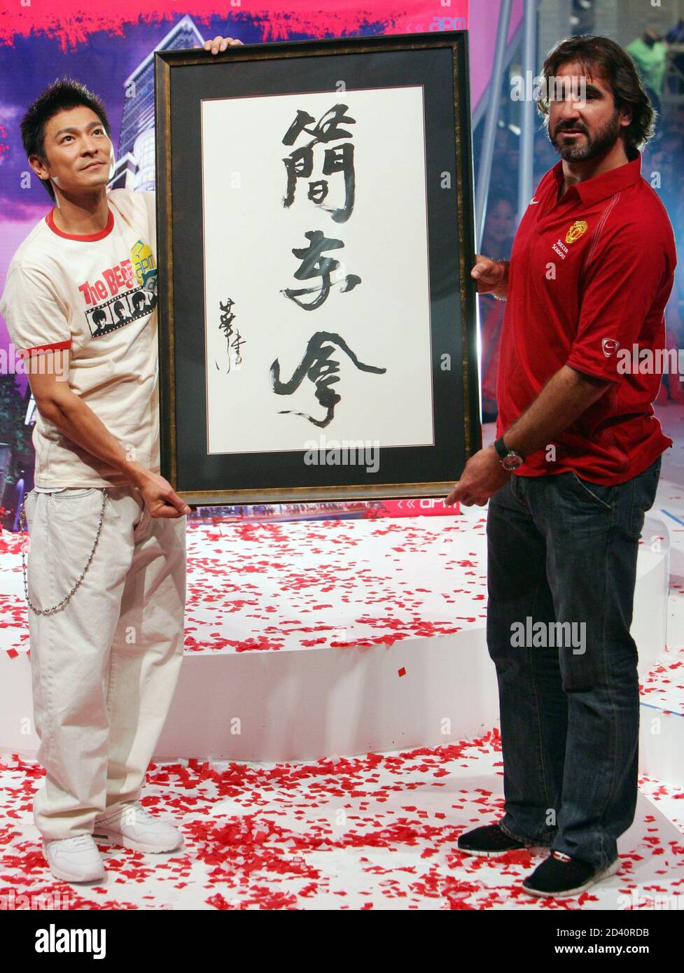 Former Manchester United player Eric Cantona (R) receives a Chinese calligraphy of his name from Hong Kong singer-actor Andy Lau as they attend a promotional event at a shopping mall in Hong Kong July 17, 2005. English team Manchester United will play against the Hong Kong National team on July 23, 2005. REUTERS/Paul Yeung  PY/JJ Stock Photo