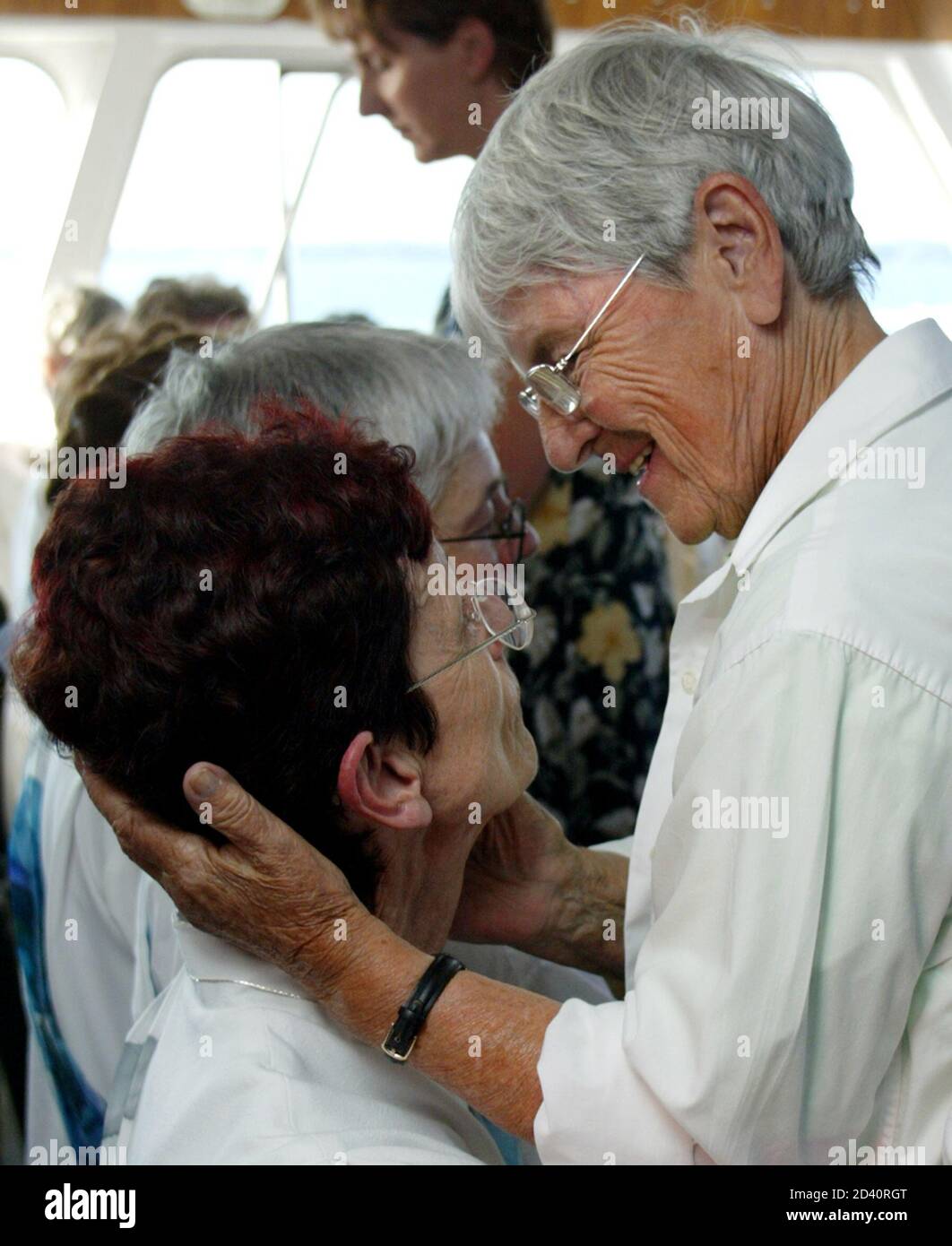 Roman Catholic Michele Birch-Conery (L) is congratulated by a supporter during a ceremony on a boat in international waters on the St. Lawrence Seaway near Gananoque, Ontario July 25, 2005. Nine North American Catholic women, including Birch-Conery, were unofficially ordained priests or deacons in an unsanctioned ceremony on Monday. The ordinations are not valid within the Catholic Church. REUTERS/Chris Wattie  CW/DH Stock Photo