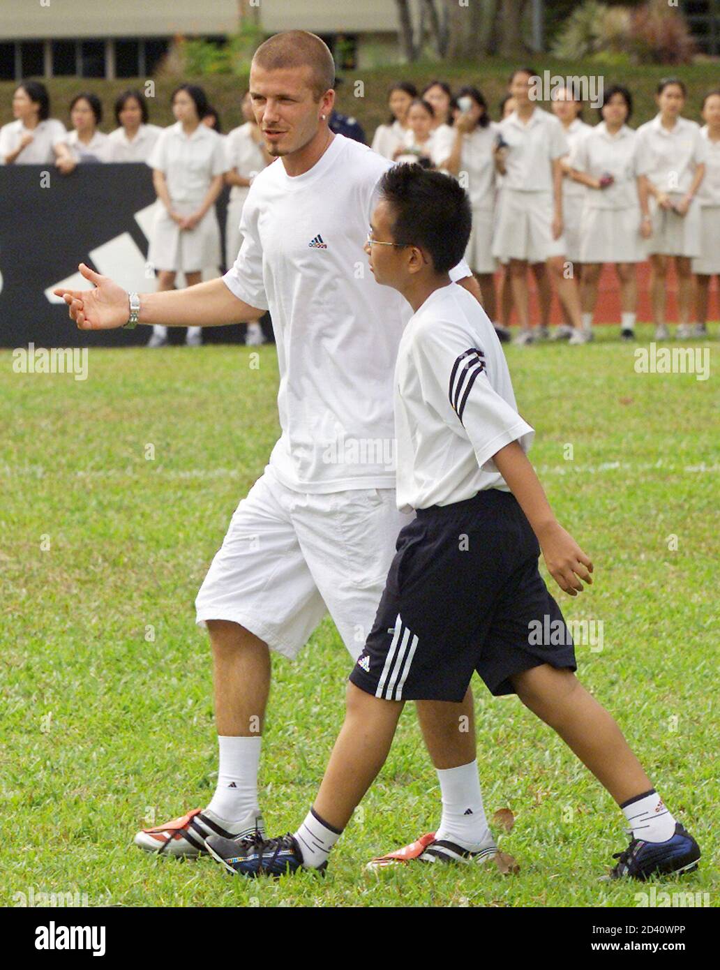 Manchester United star David Beckham gives a pointer to a youth during a  short soccer match at a clinic in Singapore July 26, 2001. Beckham is  touring through Southeast Asia with his