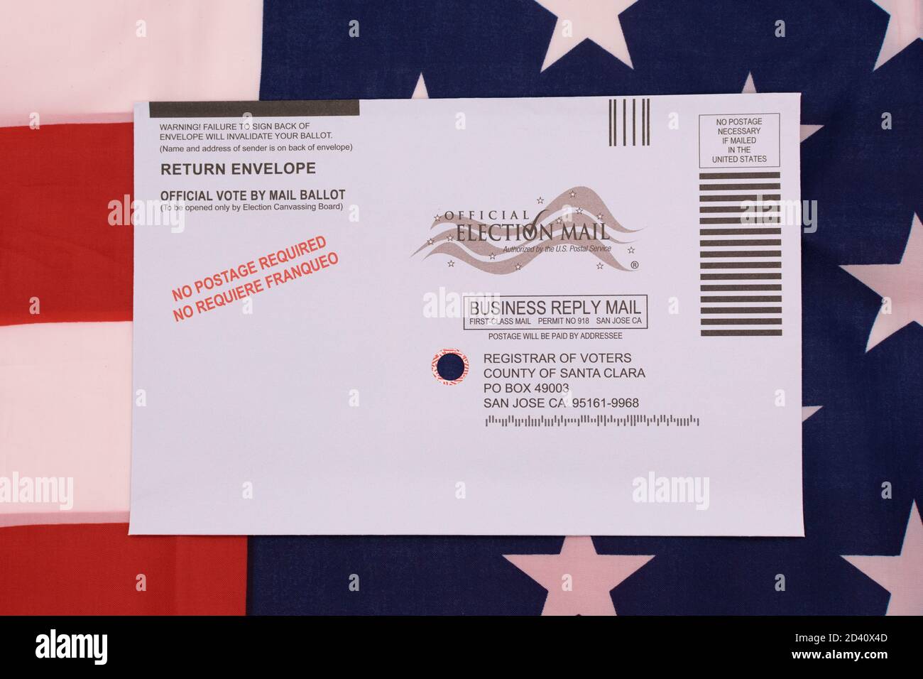Return envelope for official vote by mail ballot in Santa Clara County. Background the flag of the United States - San Jose, California, USA - October Stock Photo