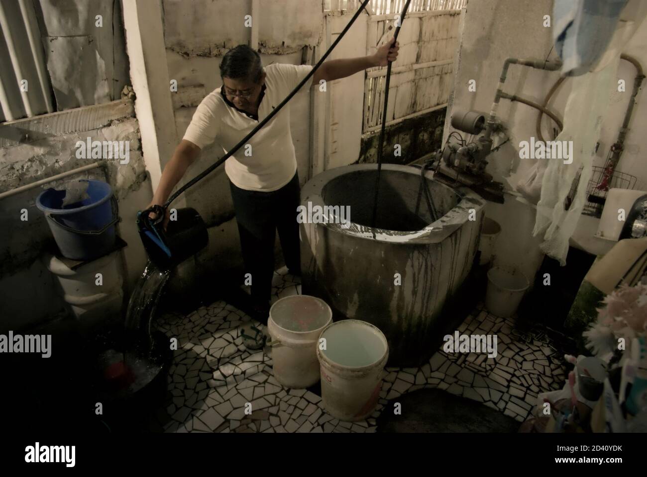 A man is photographed as he is taking water from a water well placed inside his house in a residential area of Jakarta, Indonesia. Stock Photo