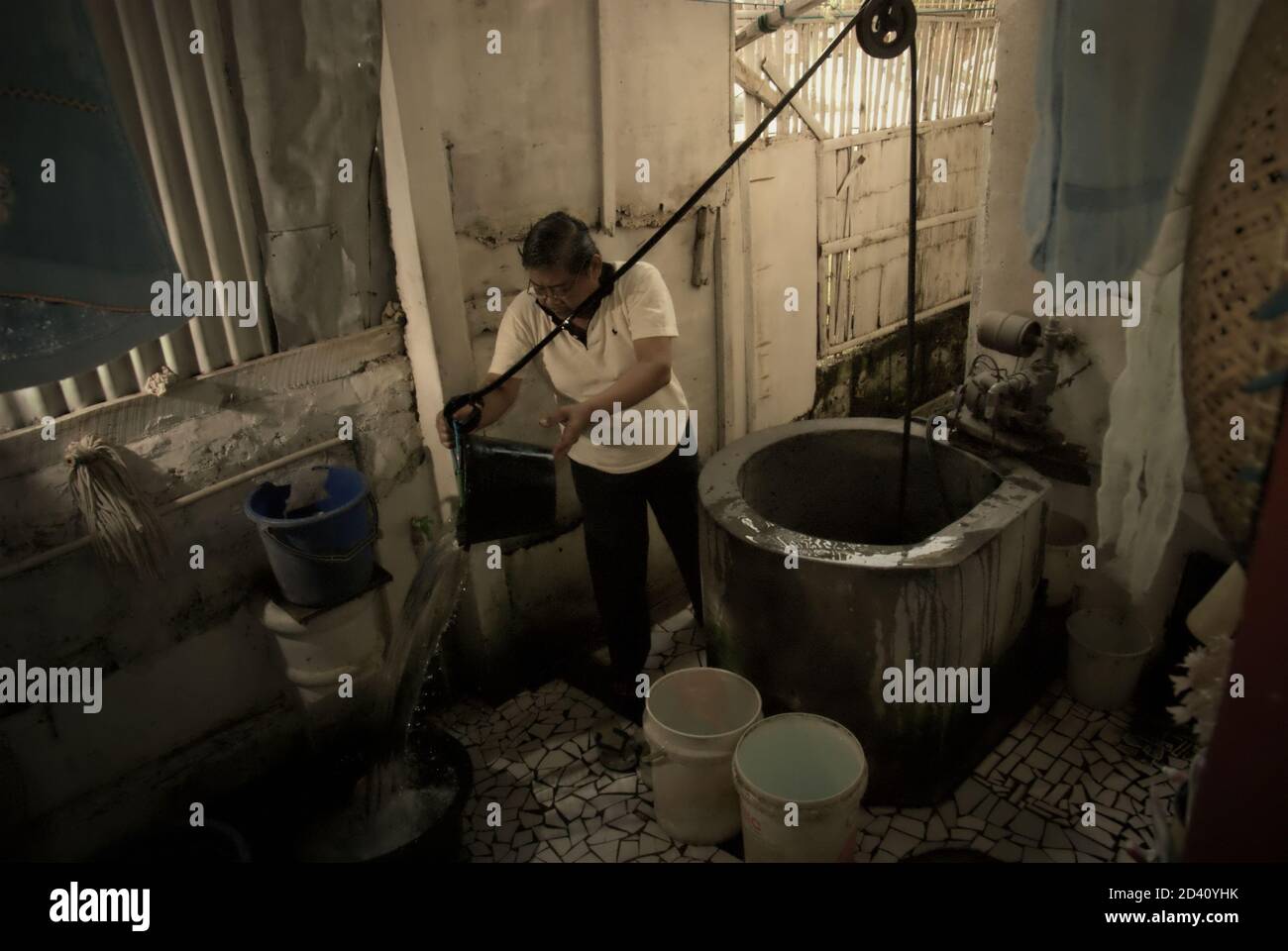 A man is photographed as he is taking water from a water well placed inside his house in a residential area of Jakarta, Indonesia. Stock Photo