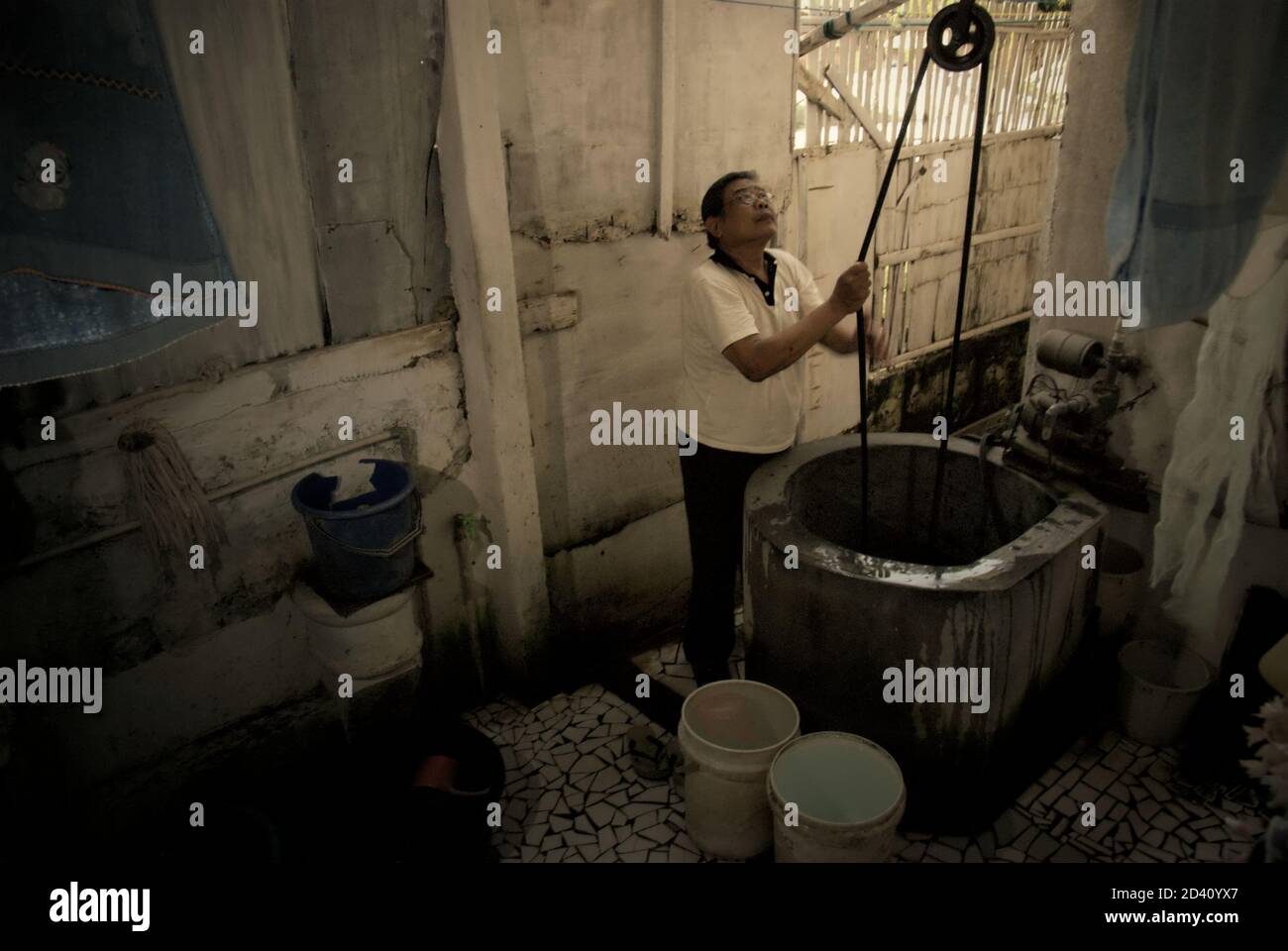 A man is photographed as he is taking water from a water well placed inside his house in a residential area of Jakarta, Indonesia. Stock Photo