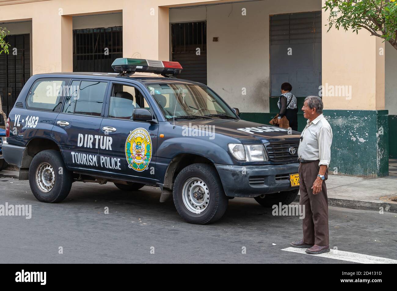 Lima, Peru - December 4, 2008: Closeup of black Tourism Police SUV Toyota car parked along street. Senior man nearby. Beige building facade in back. C Stock Photo