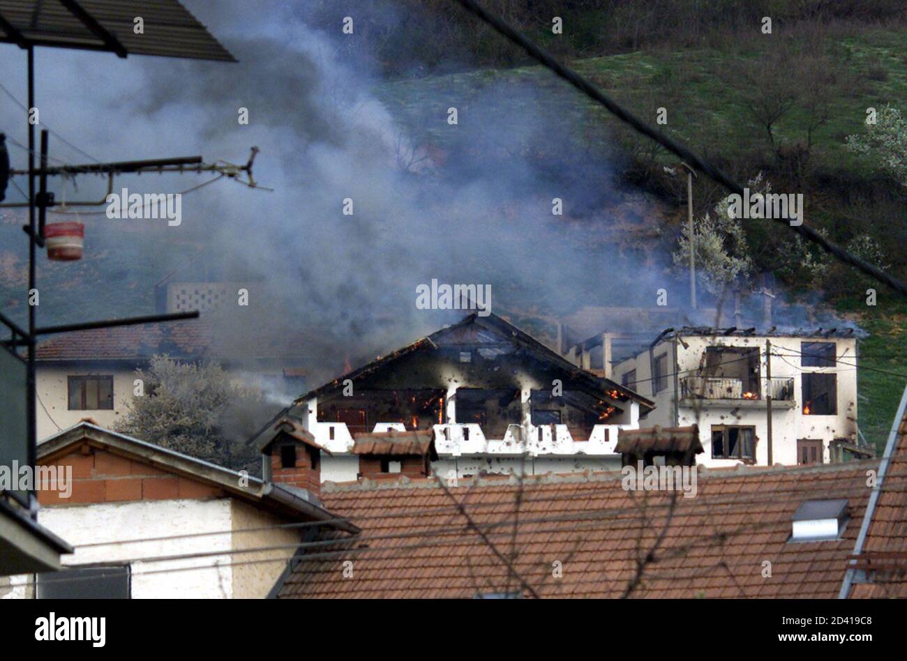 Houses burn on a hillside in a suburb of Tetovo after Macedonian police fired heavy-calibre machineguns March 20, 2001. A few curious onlookers ventured close to sandbagged police positions near the city football stadium to witness the seventh day of heavy shooting against ethnic Albanian guerrilla positions.  LB/WS Stock Photo