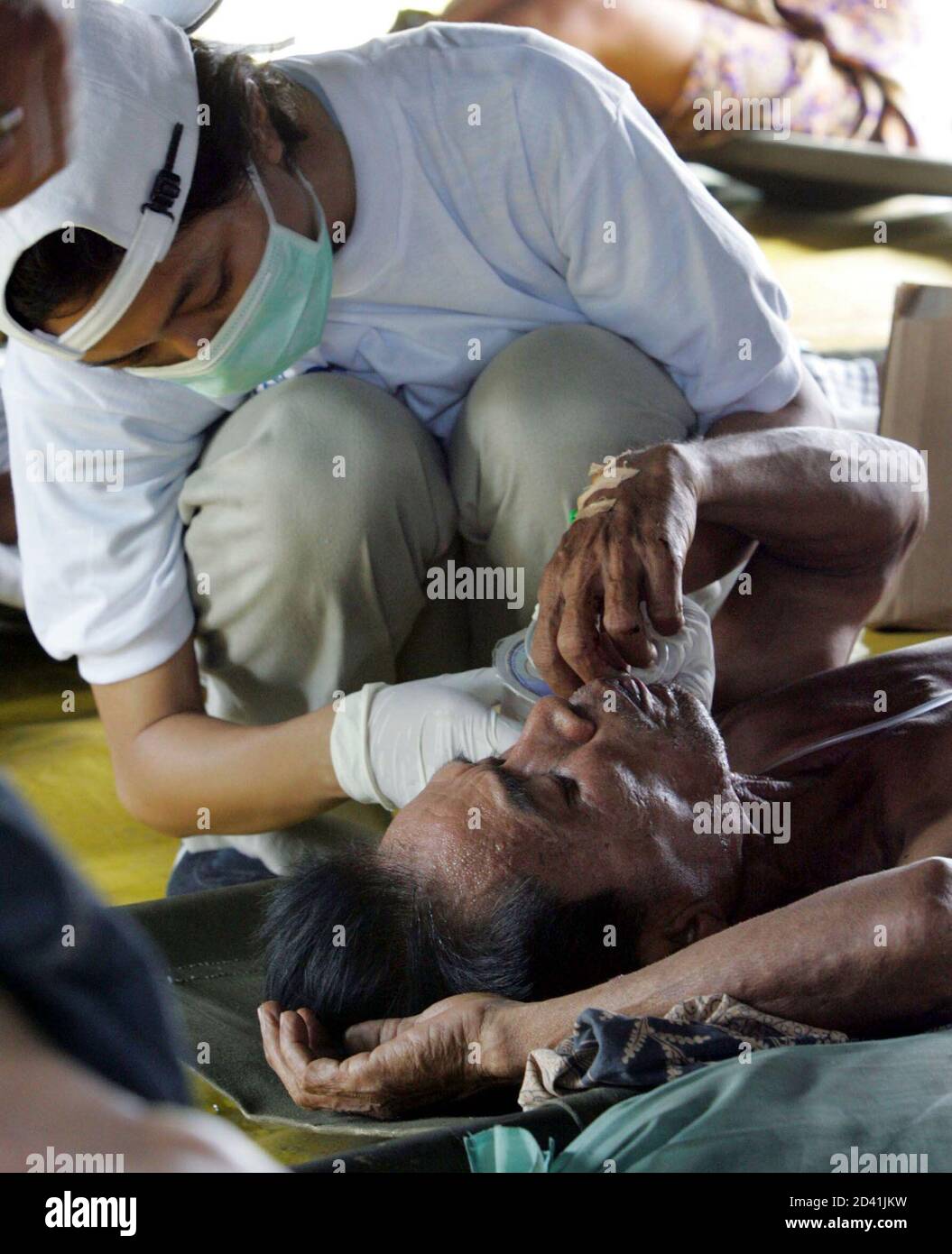 A tsunami survivor is treated by a medic in a makeshift clinic at Banda Aceh airport, Indonesia. Aid workers cleared landing strips in Asia's flooded tsunami-hit regions to start flying food, clean water and doctors to hungry and injured survivors, but the global relief operation continued to struggle on Tuesday. REUTERS/Yuriko Nakao  YN/FA Stock Photo