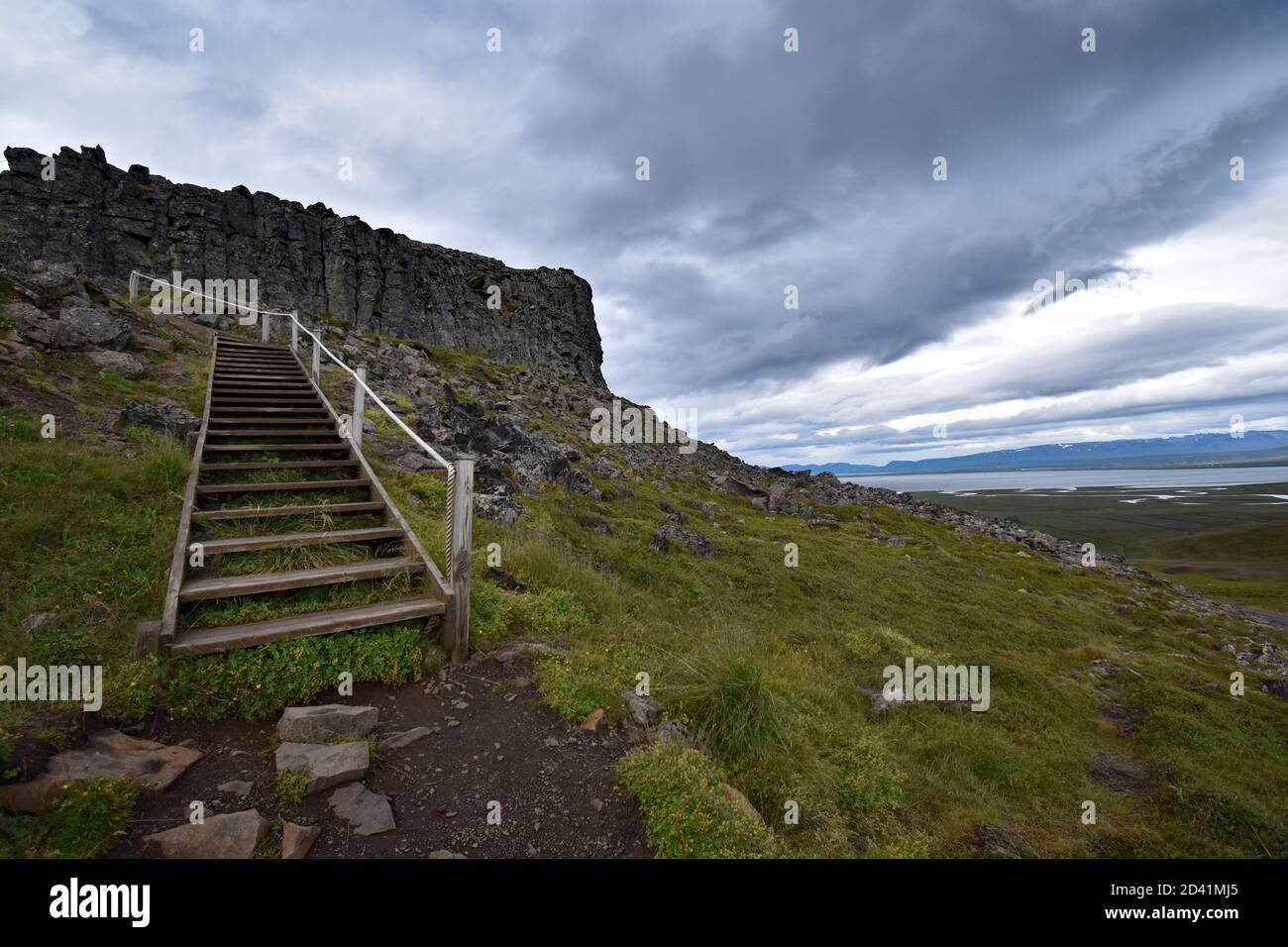 Borgarvirki in the Vatnsnes Peninsular in Northern Iceland. A wooden staircase leads up to the top of the rock formation. Dramatic clouds fill the sky Stock Photo