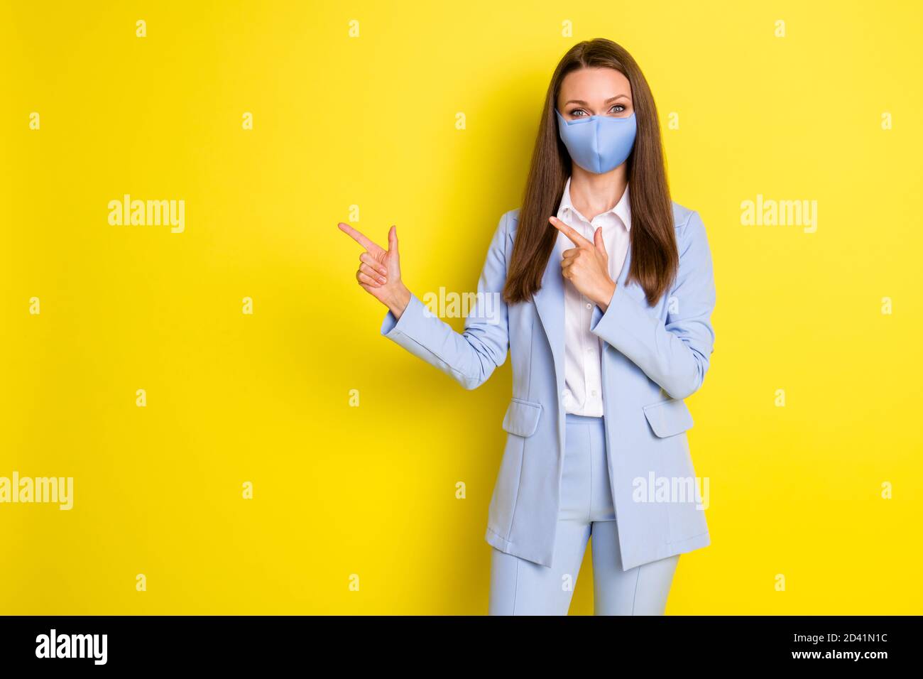Photo of boss executive business lady point index finger copyspace present covid ads promotion wear blue jacket blazer pants trousers medical mask Stock Photo