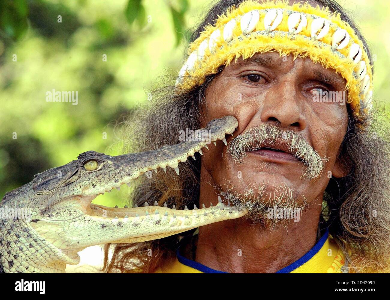 66 yr-old Mexican Eroberto Piza Rios, better known as 'Tamacun,' gets a love-bite from his crocodile during a show in Playa Linda Ixtapa in the Mexican State of Guerrero in this photo taken August 1, 2003. Tamacun has rised and trained at least 47 crocodiles which grow up to five meters in length. Tamacun wears the yellow jersey of his favorite mexican soccer team 'America' and also names his crocodiles after former players. REUTERS/Daniel Aguilar TO MATCH FEATURE STORY MEXICO-CROCODILES  DA Stock Photo