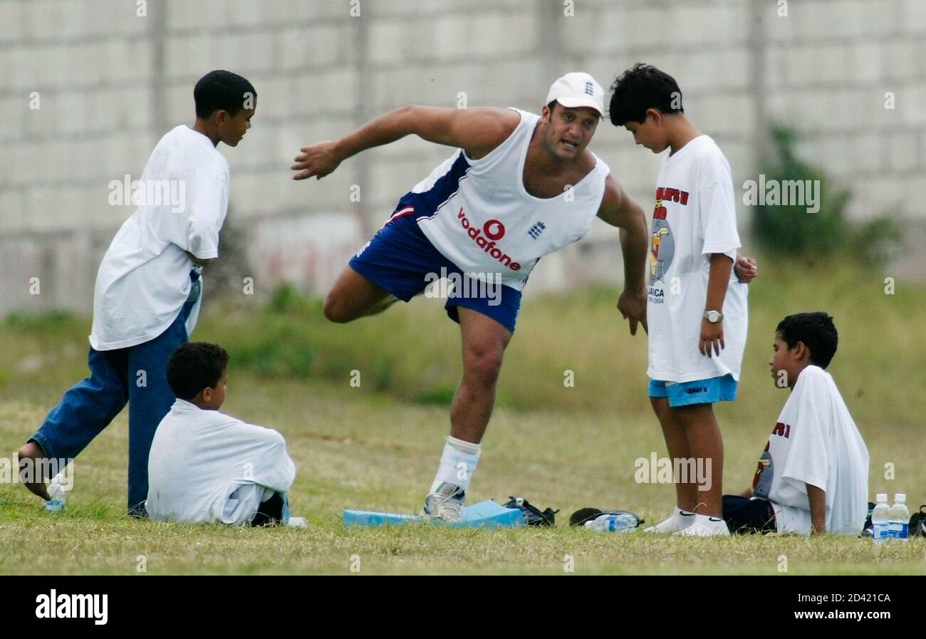 Mark Butcher of England exercises his injured left foot alongside local kids, at the Sir Frank Worrel Cricket Grounds at the University of West Indies, March 6, 2004 in Kingston, Jamaica. Butcher's foot has been improving after he injured it during the first three day warmup match earlier in the week. REUTERS/Andy Clark  AC/GN Stock Photo