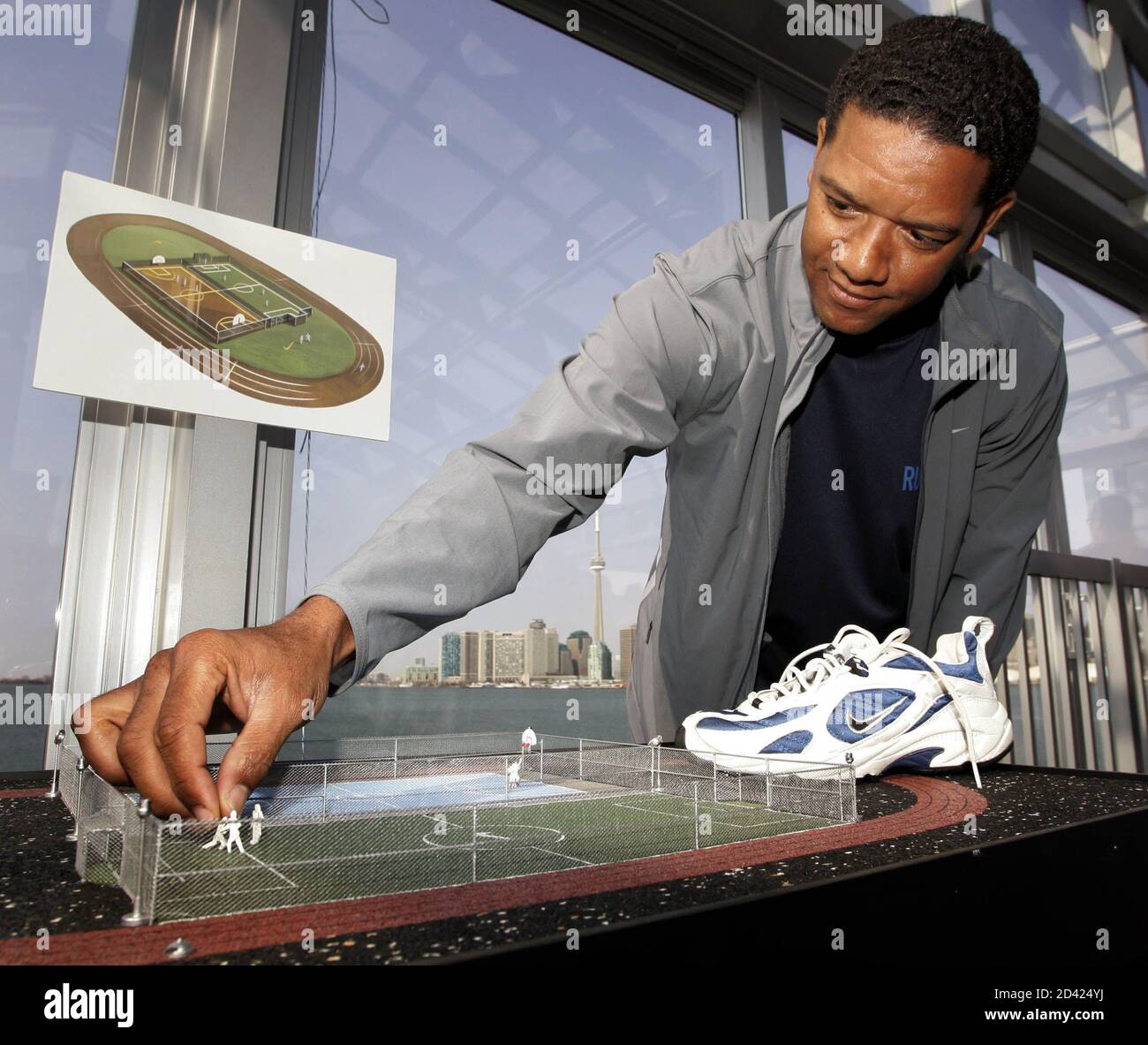 Toronto Argonaut quarterback Damon Allen adjusts a miniature soccer player  on a model of a sports complex which Nike Canada announced will be built  out of 'Nike Grind' (recycled shoe material) at