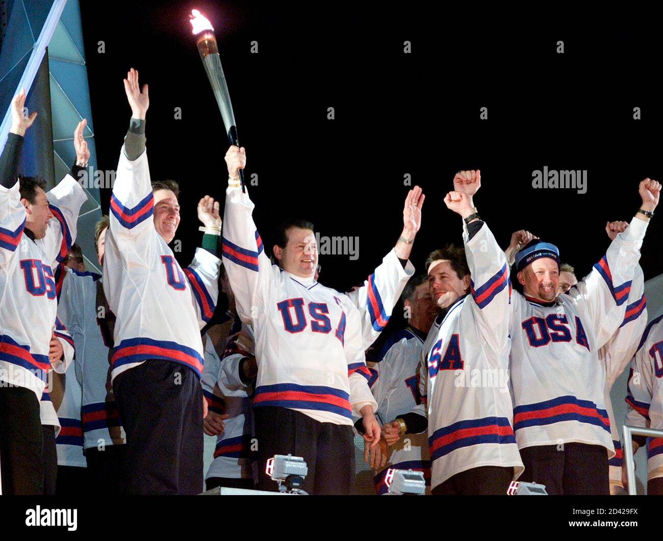 Members of the 1980 United States Olympic hockey team that won the gold  medal in Lake Placid, wave as their former team captain, Mike Eruzione,  holds the Olympic torch during the opening