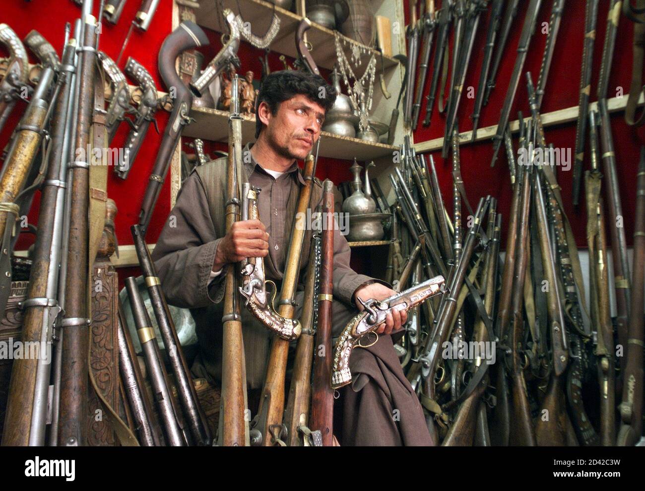 An Afghan shopkeeper lifts an antique rifle at his shop in Kabul on April  5, 2003. The price of a piece depends on its age and quality and can reach  as much