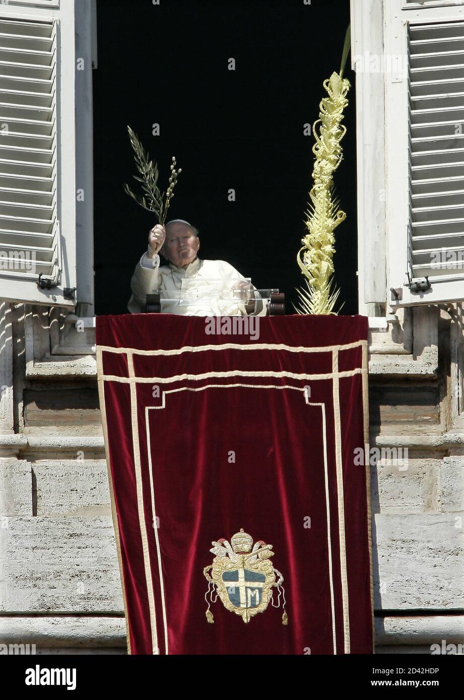 Pope John Paul II holds an olive branch as he appears at the window of his  private apartments at the end of the Palm Sunday mass in Saint Peter Square  at the