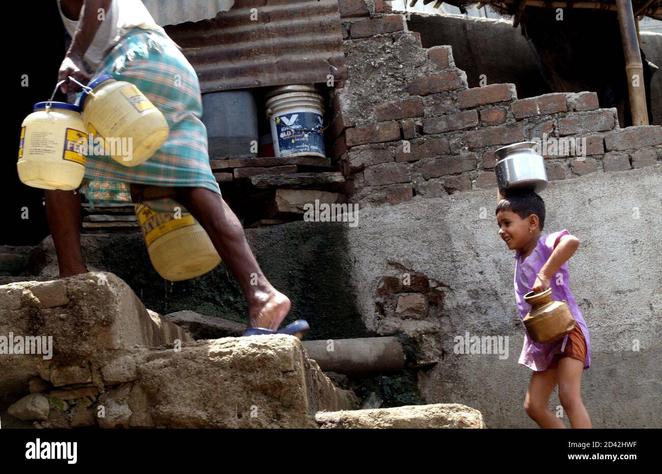 Kanika, a girl living in a slum, carries water pots home at a suburb in Bombay May 24, 2005. At present nearly 30 percent of Bombay's 18 million people live in slums without adequate supply of piped water. As more of them move into multi-storeyed buildings with piped water in every house, the demand for water is expected to skyrocket, according to the Indo-Asian News Service. REUTERS/Adeel Halim AD/LA Stock Photo