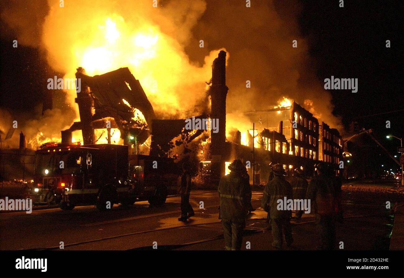 Detroit firefighters stand back as a wall of an abandoned, four-story brick warehouse that is completely engulfed in flames collapses in mid-town Detroit, Michgan June 20, 2005. The historic building covers an entire city block and originally housed automotive companies in Detroit, including Studebaker. About 130 firefighters fought the five alarm fire, attempting to keep it from spreading to surrounding neighborhoods. REUTERS/Rebecca Cook  RC/CCK Stock Photo