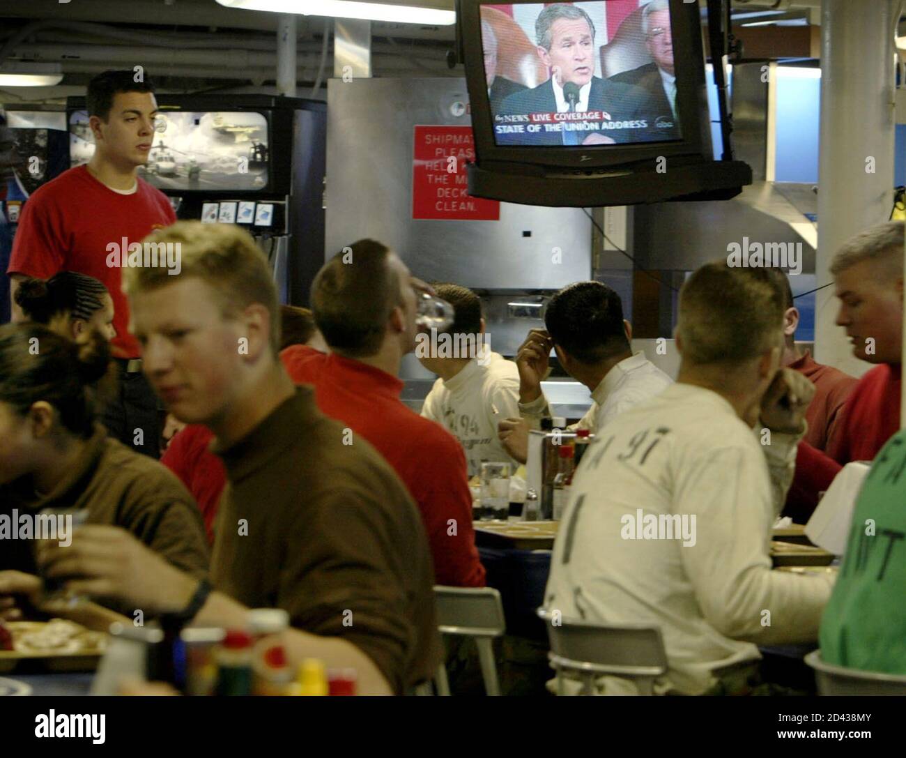Sailors eat their dinner as President George W. Bush, on a satellite television feed from Washington D.C., delivers his State of the Union Address as they sit in the mess hall aboard the aircraft carrier USS Nimitz 100 miles off the coast of California, January 28, 2003. The Nimitz and it's battle group are on the final days of training and are awaiting orders to deploy to the Middle East. REUTERS/Mike Blake  MB/ME Stock Photo
